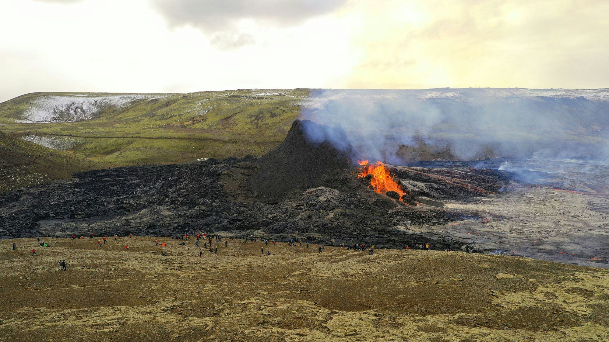 A large crowd of spectators gathers around the eruption