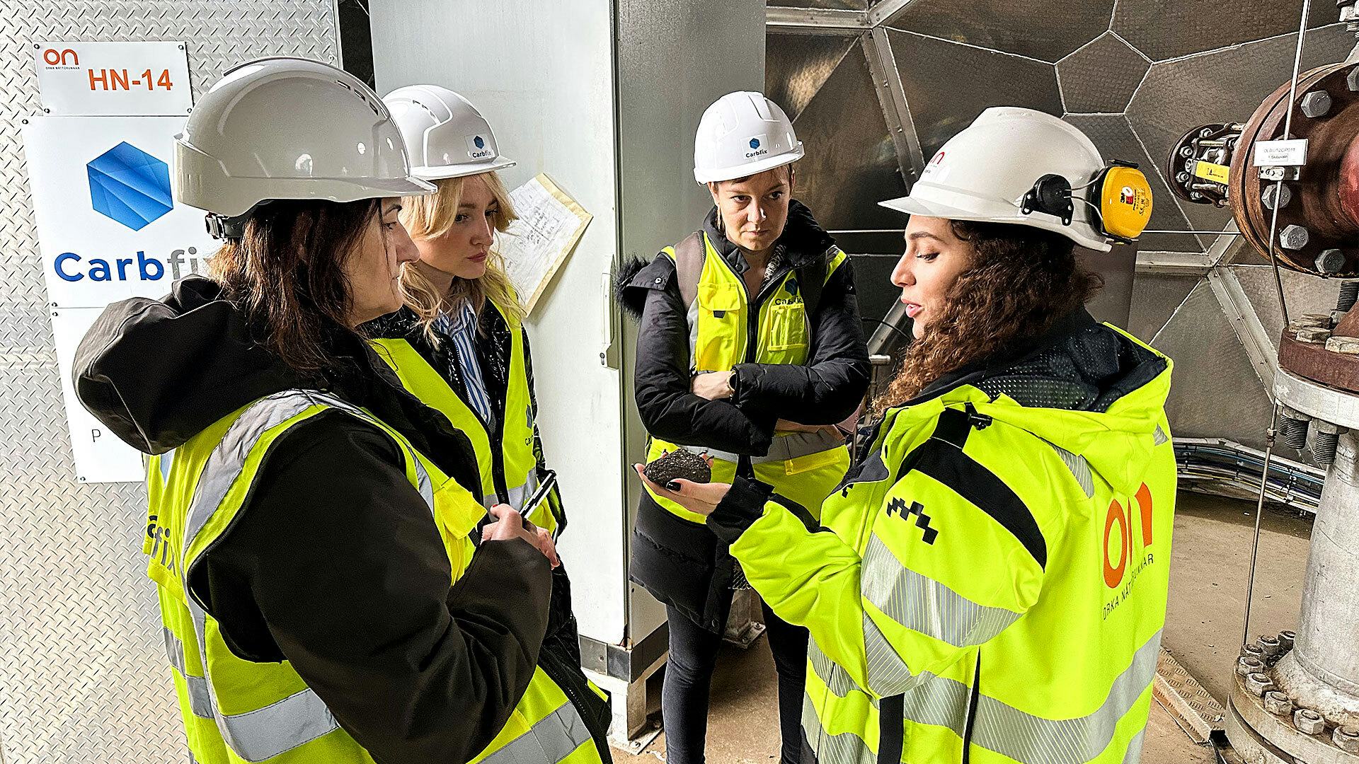 Four women discussing about rock, wearing construction vest and white helmet 