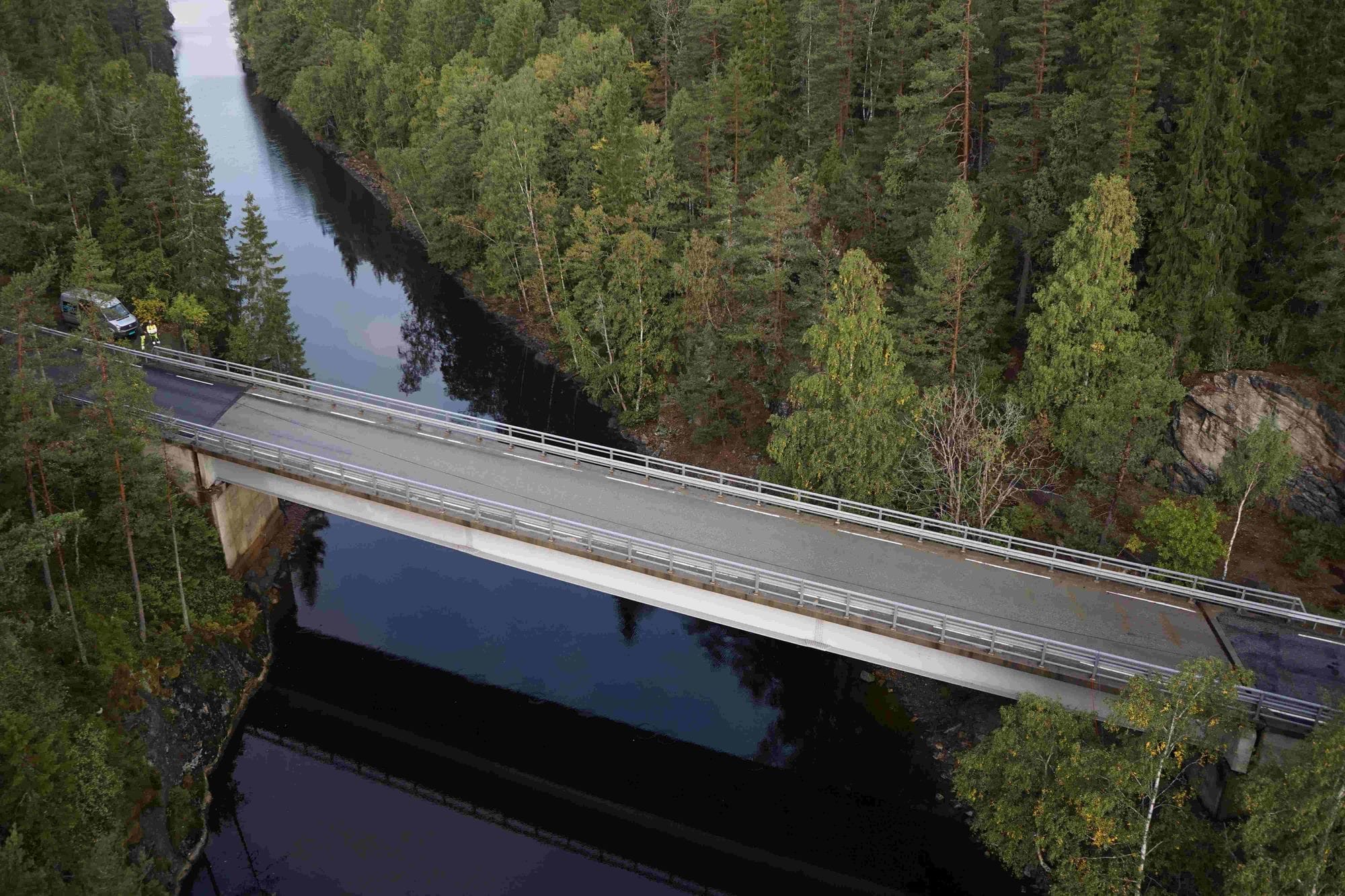 Steinsbrua bridge seen from above going over a lake and surrounded by green pine forest