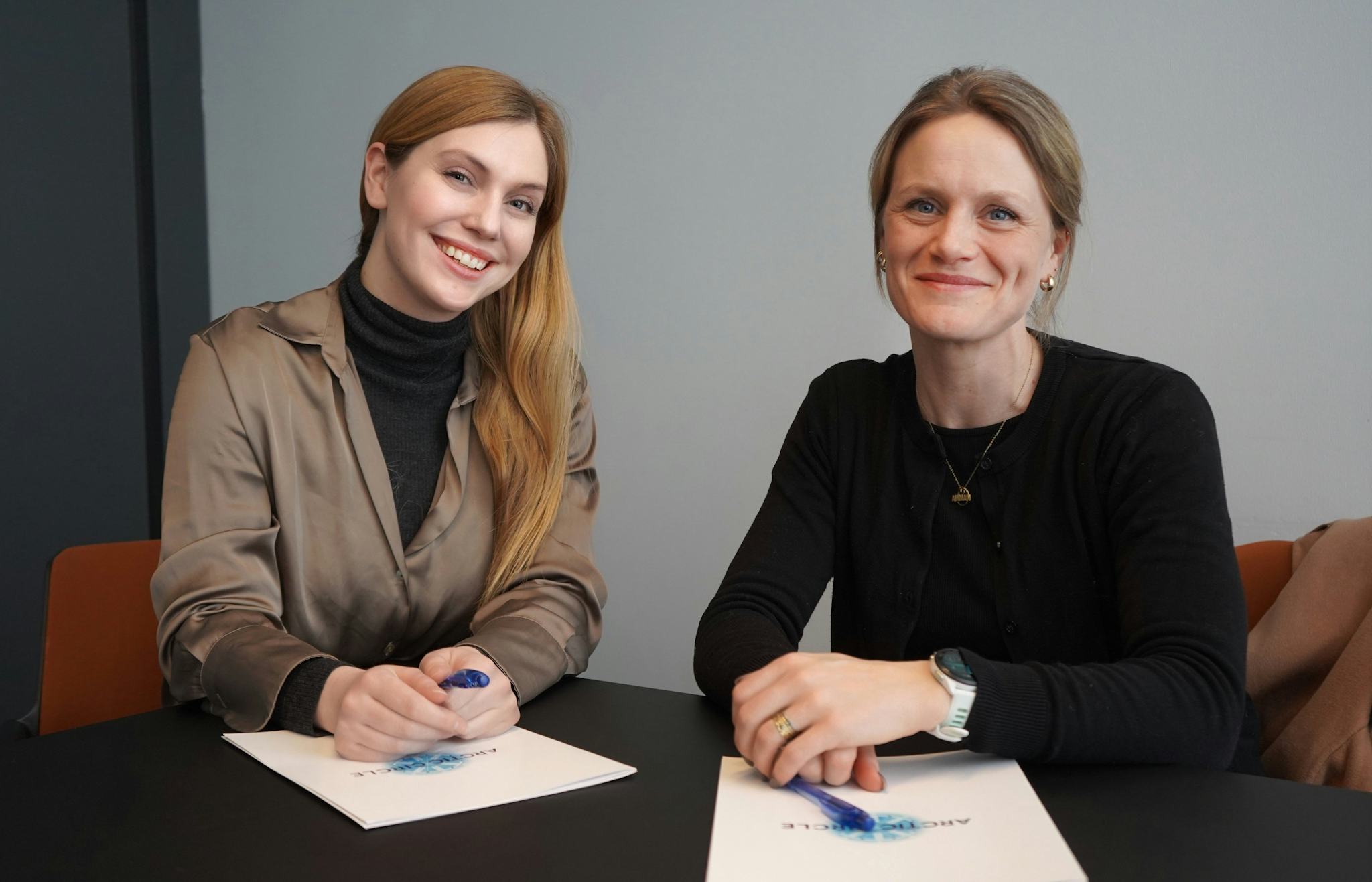 Two women sign a contract.