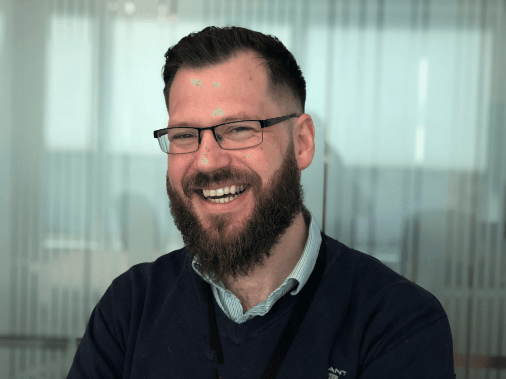 A smiling man with glasses and dark hear and beard