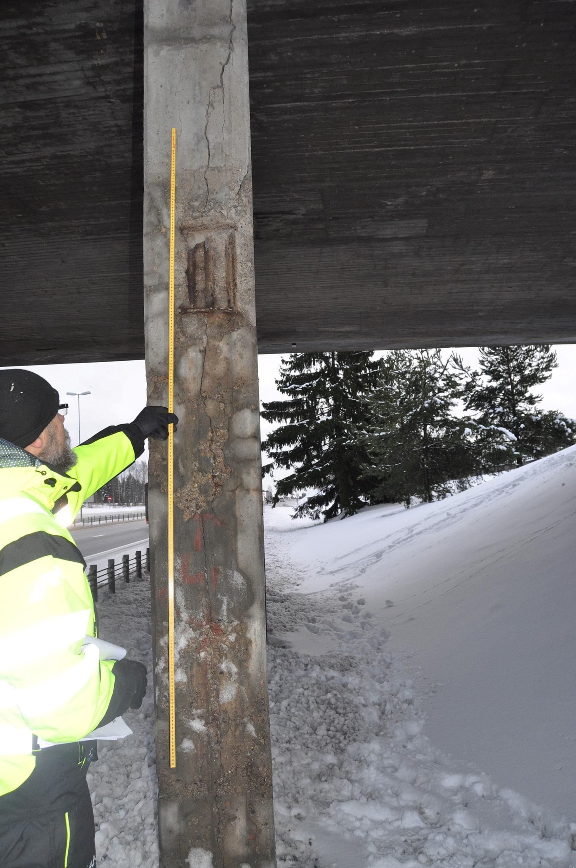 Engineer from EFLA wearing yellow clothing during inspection and measurement of damaged concrete timber and pillars on the Halmstad bridge.
