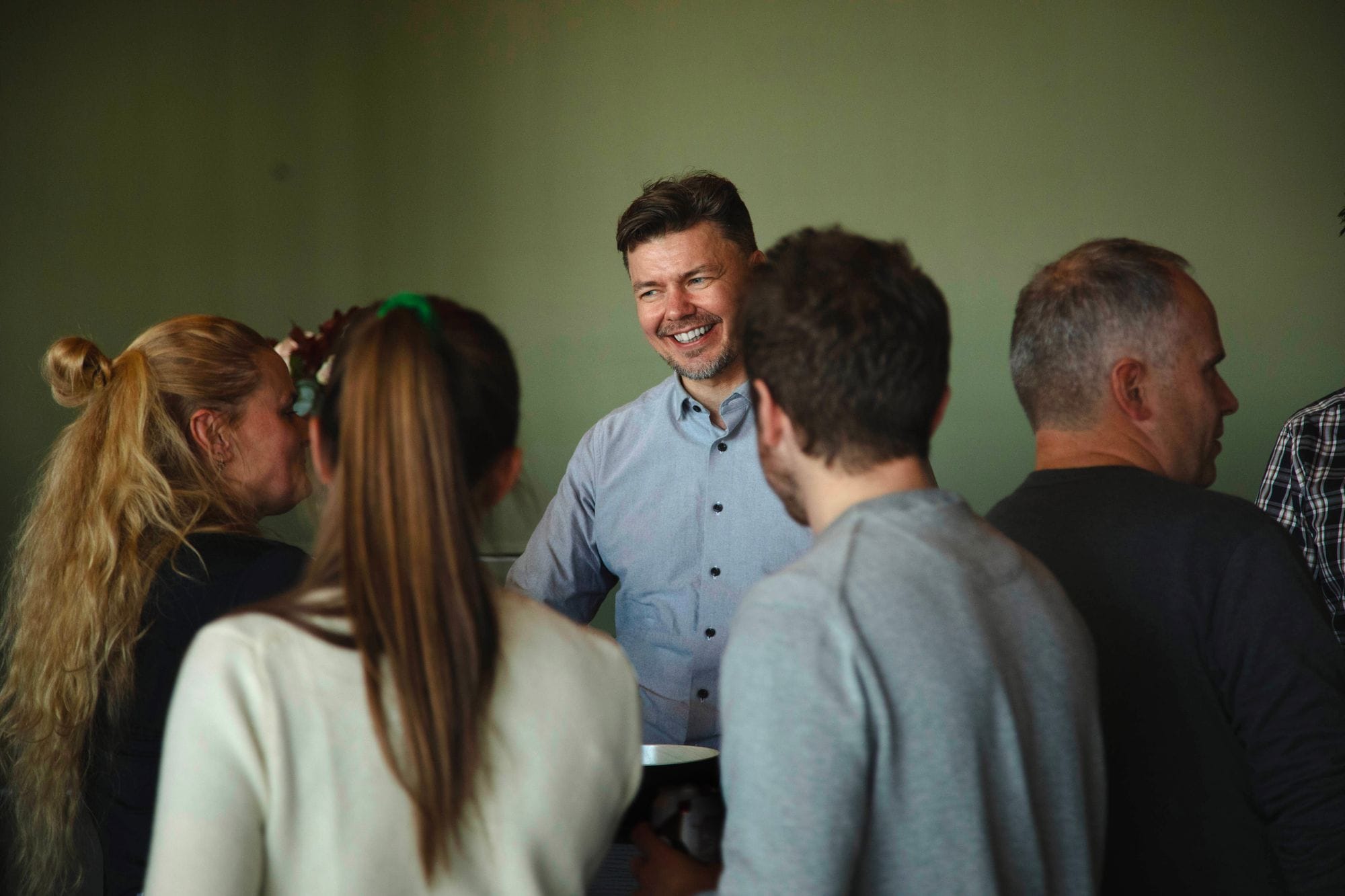 people standing in a group, a man is smiling, green background