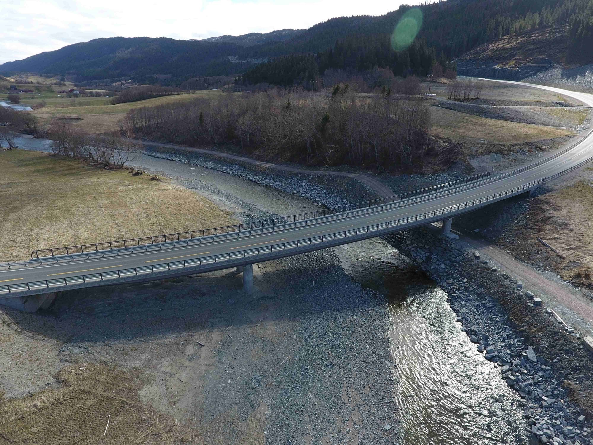 A road with a barrier crosses a river