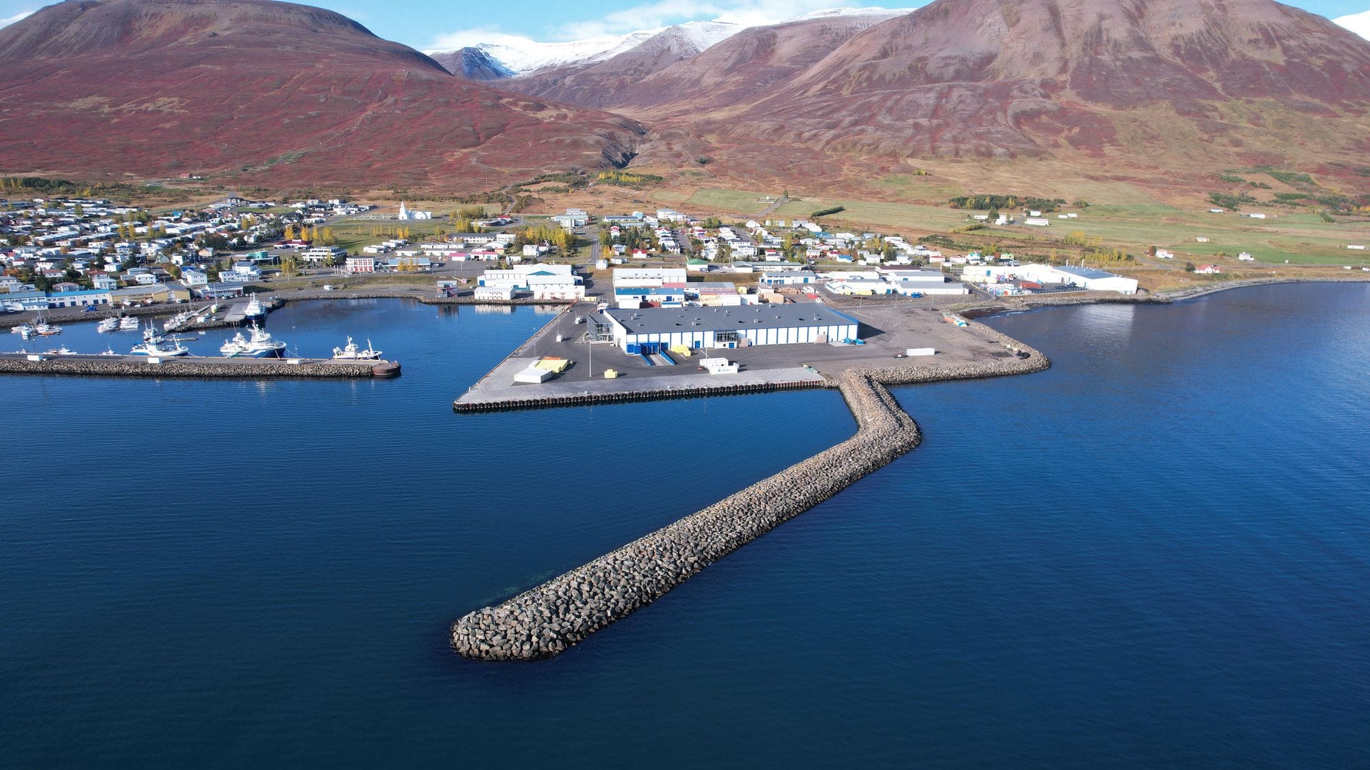 A port by the sea and a village seen from the air, mountains in the background