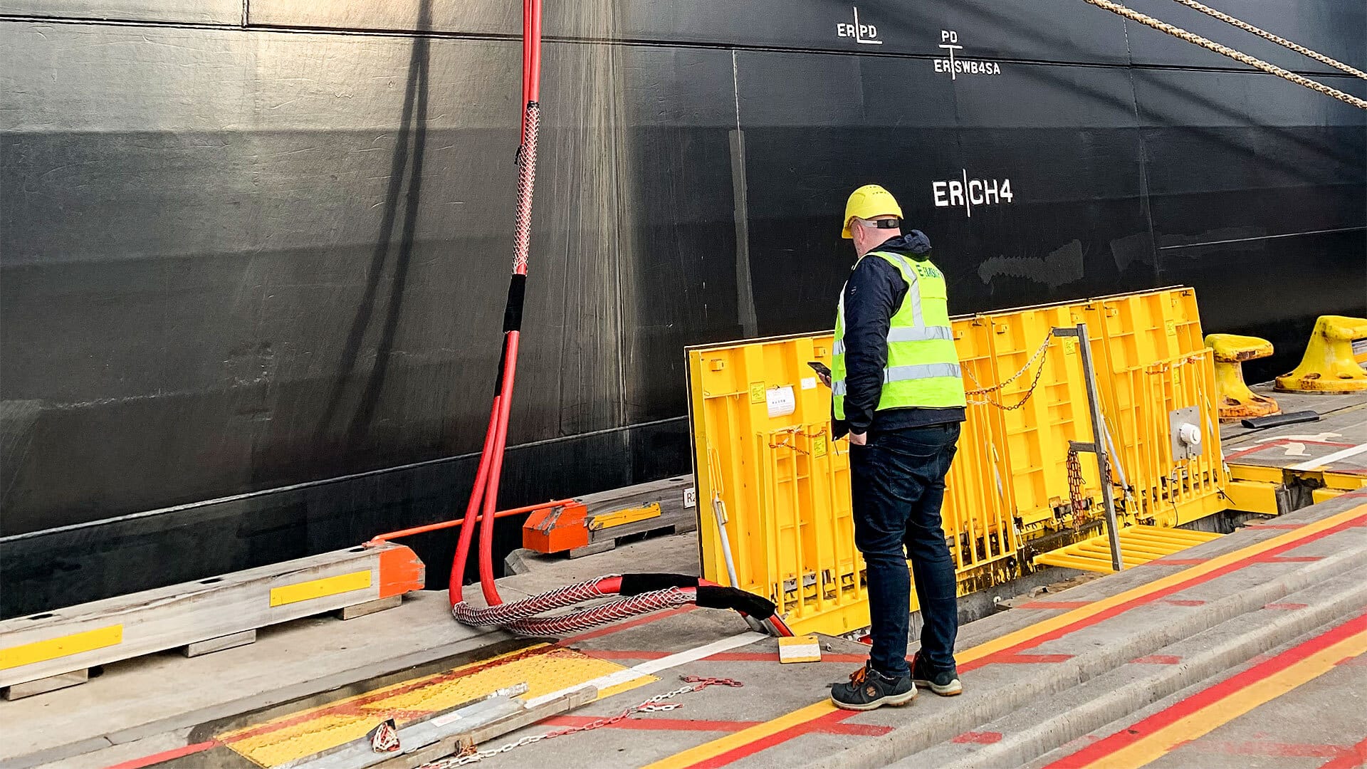 A man wearing construction vest looking at the charging cords at a harbour