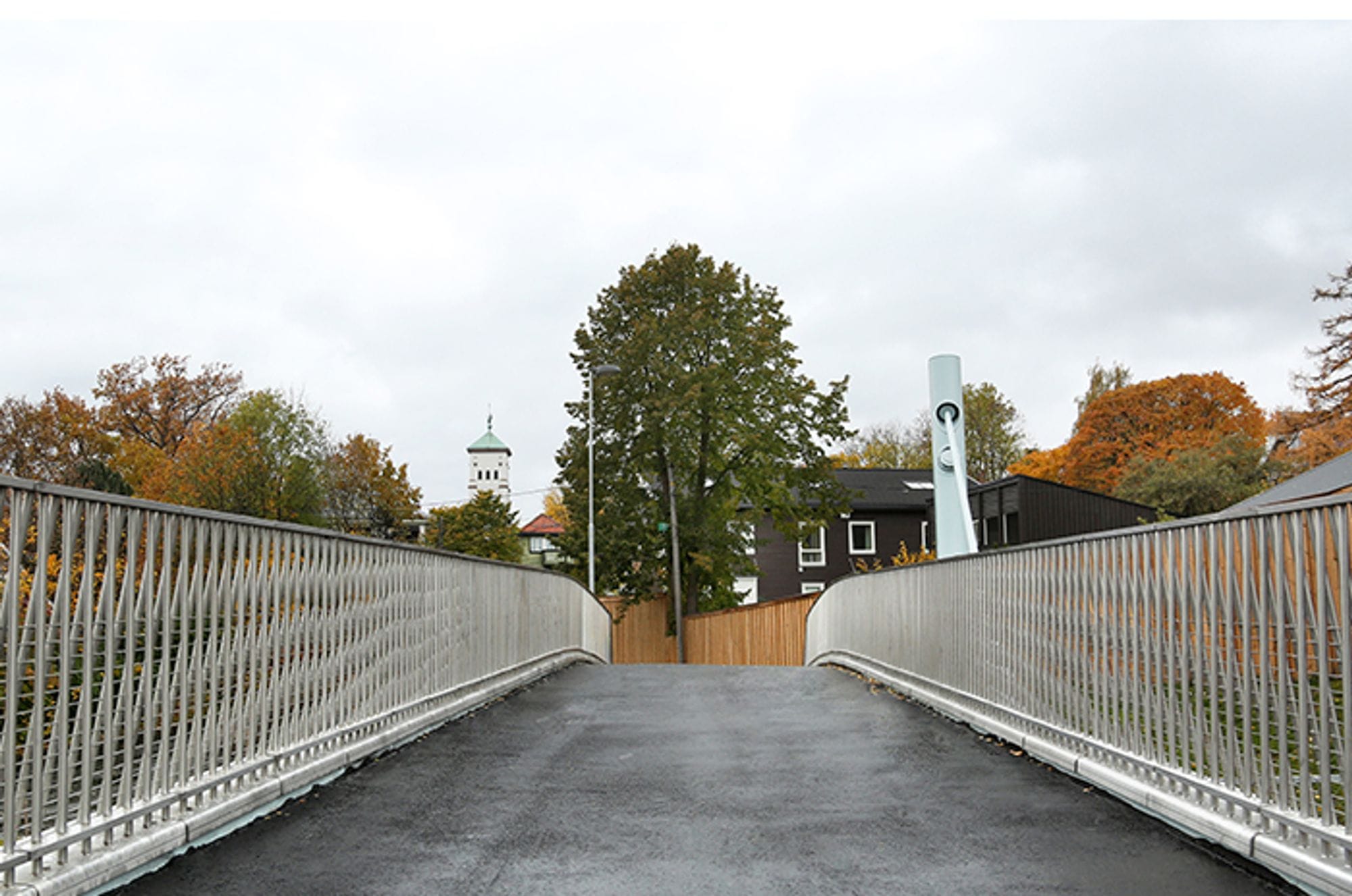 A footbridge leading to black house behind fence