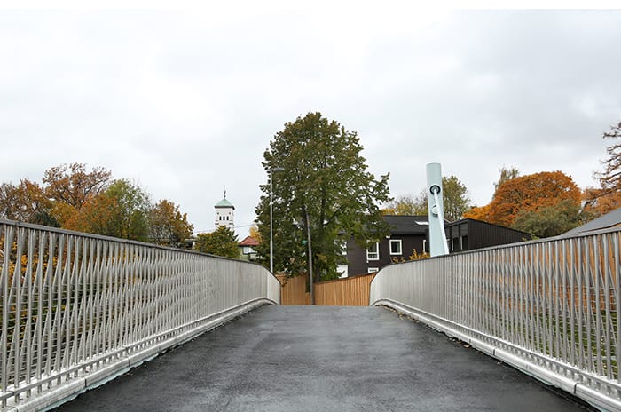 A footbridge leading to black house behind fence