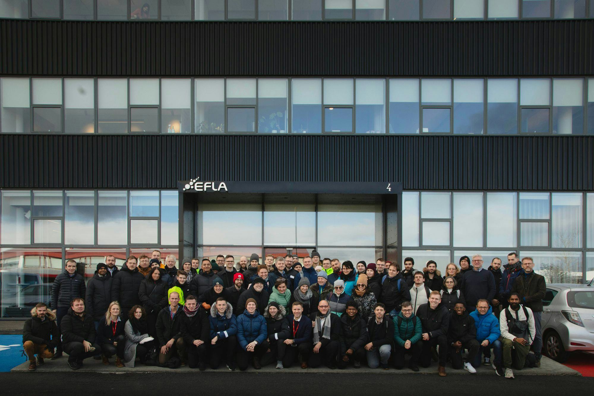 A big group of people posing in front of a black office building