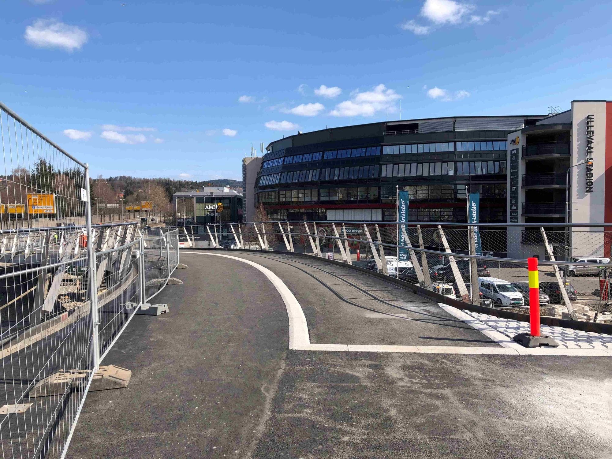 Footbridge iunder construction in front of a building and blue skies