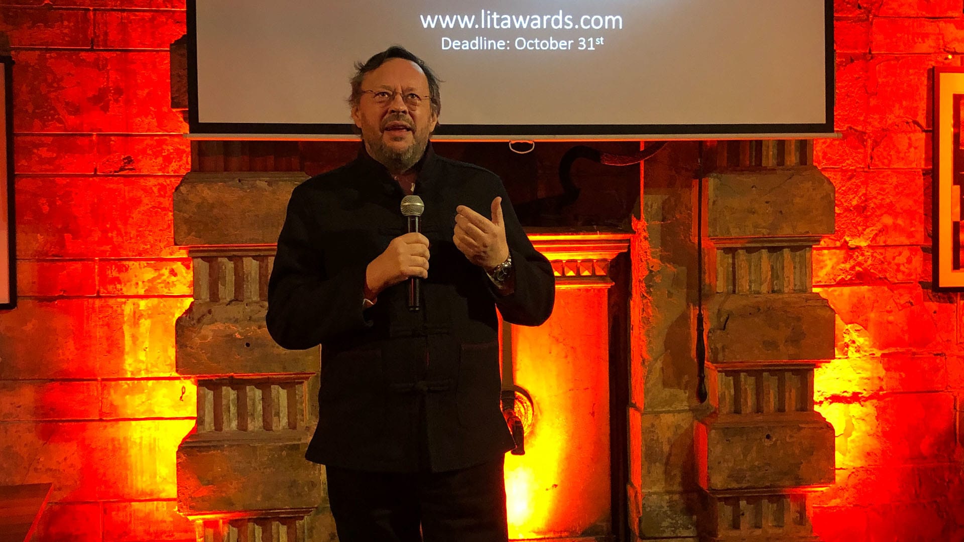 A man wearing a black suit holding a mic
