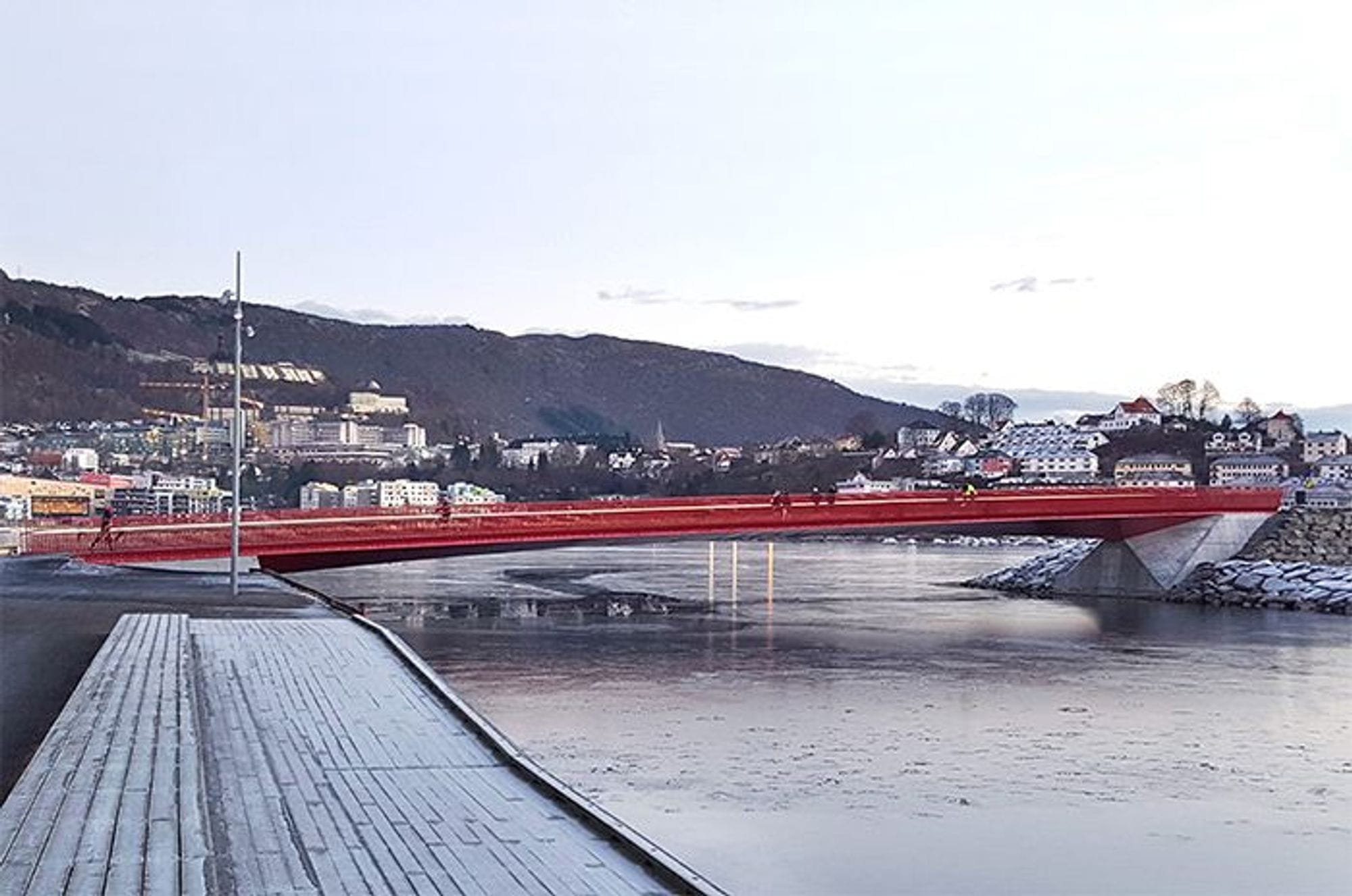 Nonnekloppen red steel box bridge and people walking over and buildings and moutain in the back.