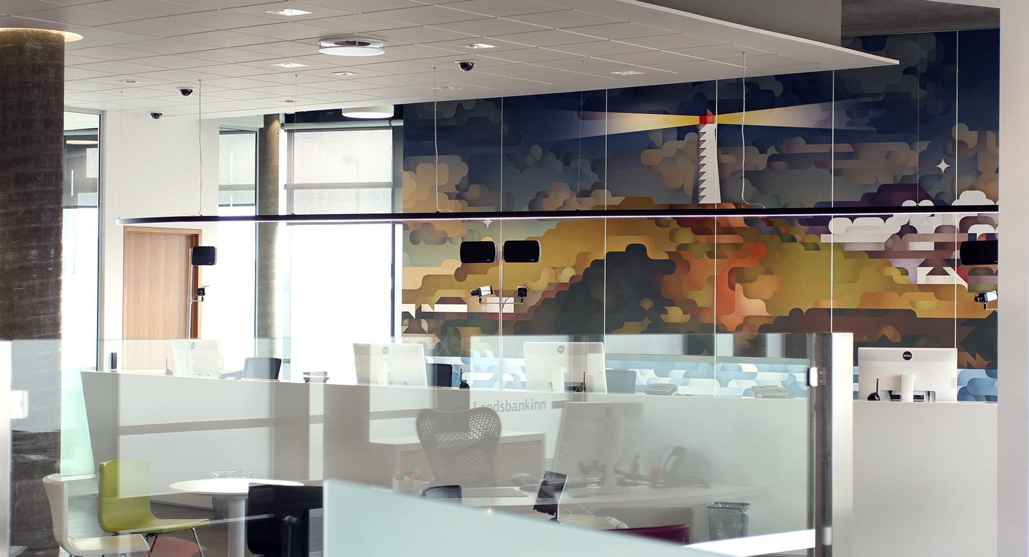Inside an office building, glass panels between desks and painted mural on a wall
