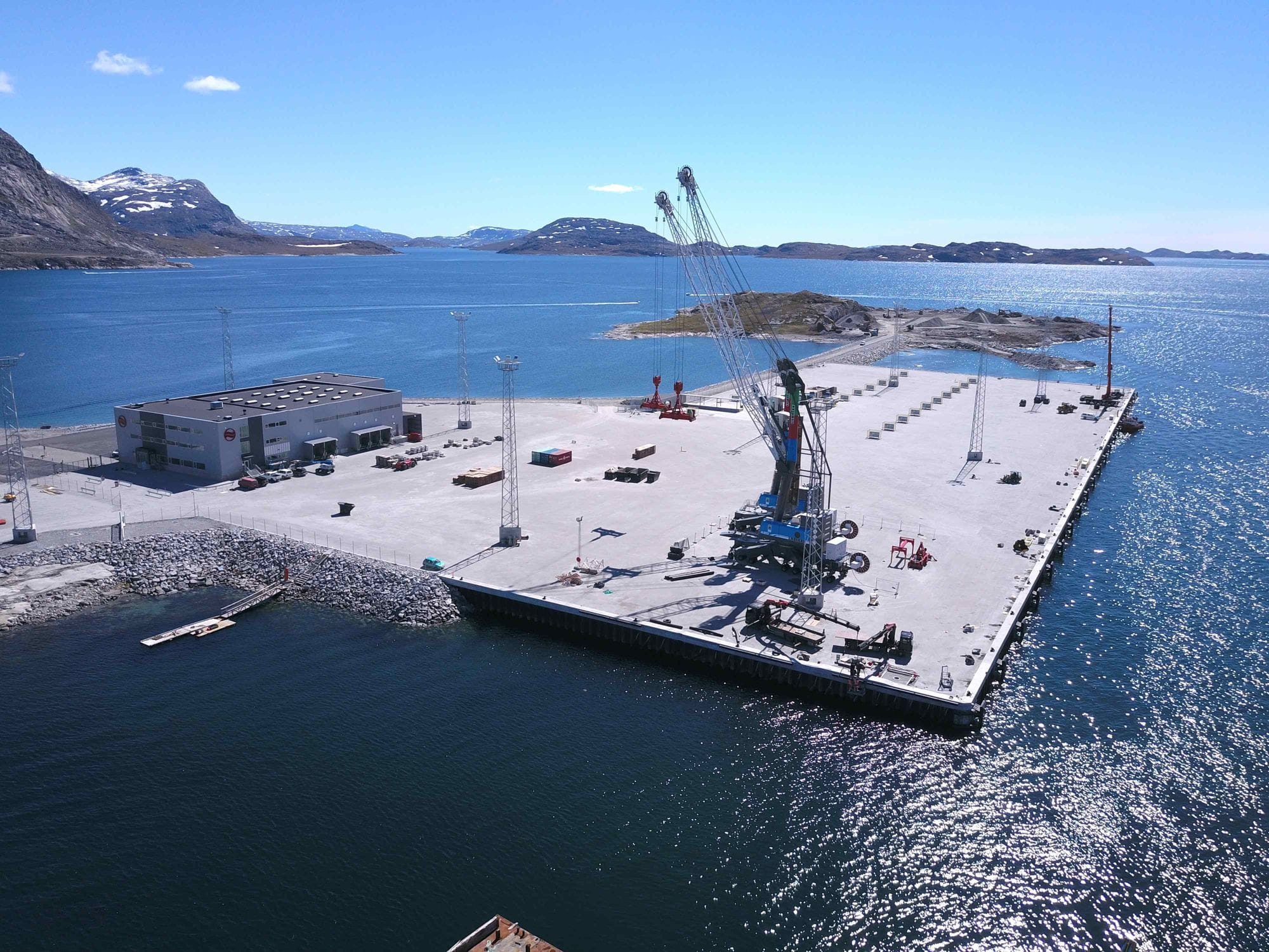Large boat port seen from above and closup with big buildings on it, cranes and surrounded by the sea and mountains