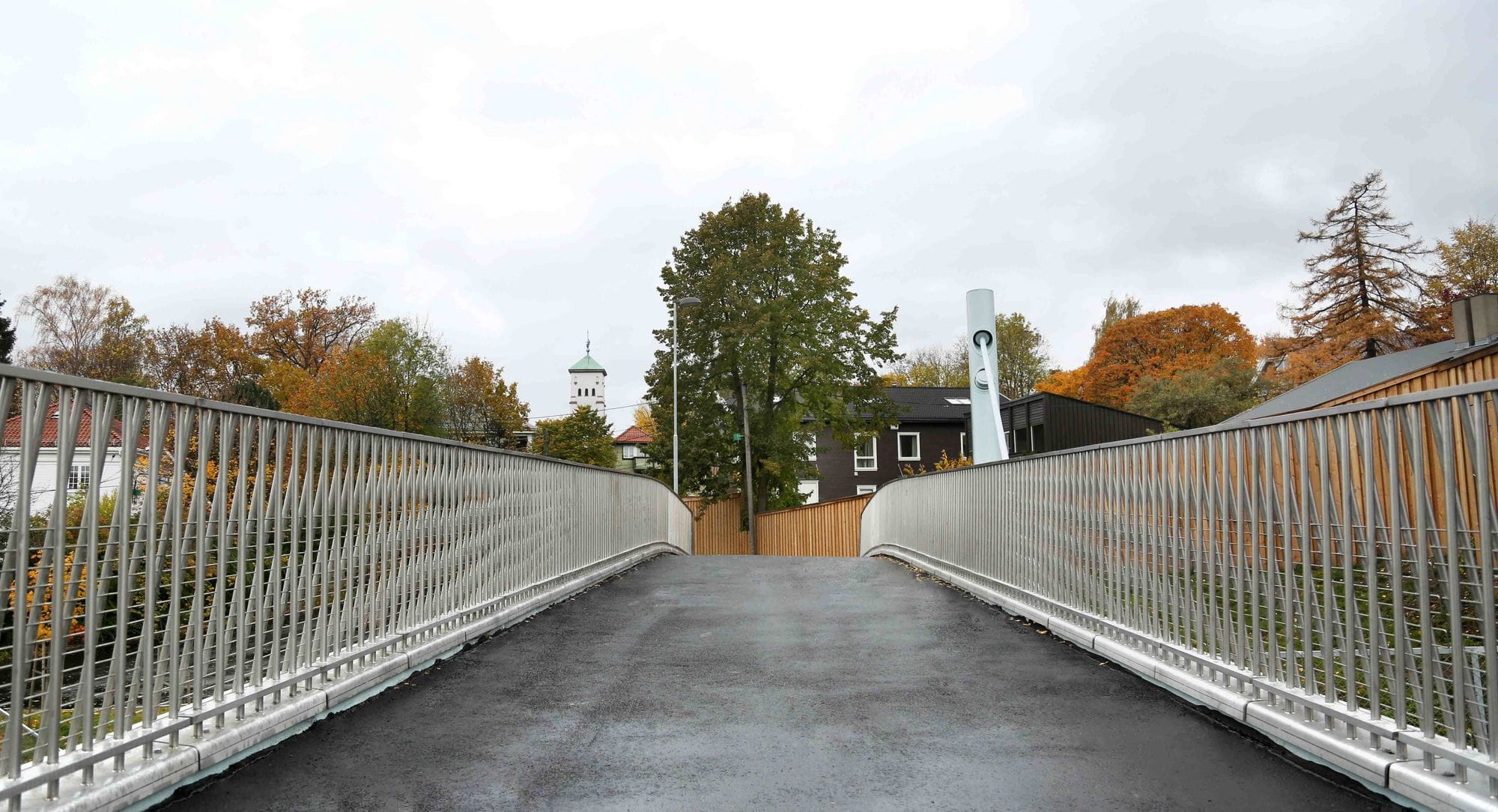 looking over a bridge, buildings and trees at the end of the bridge