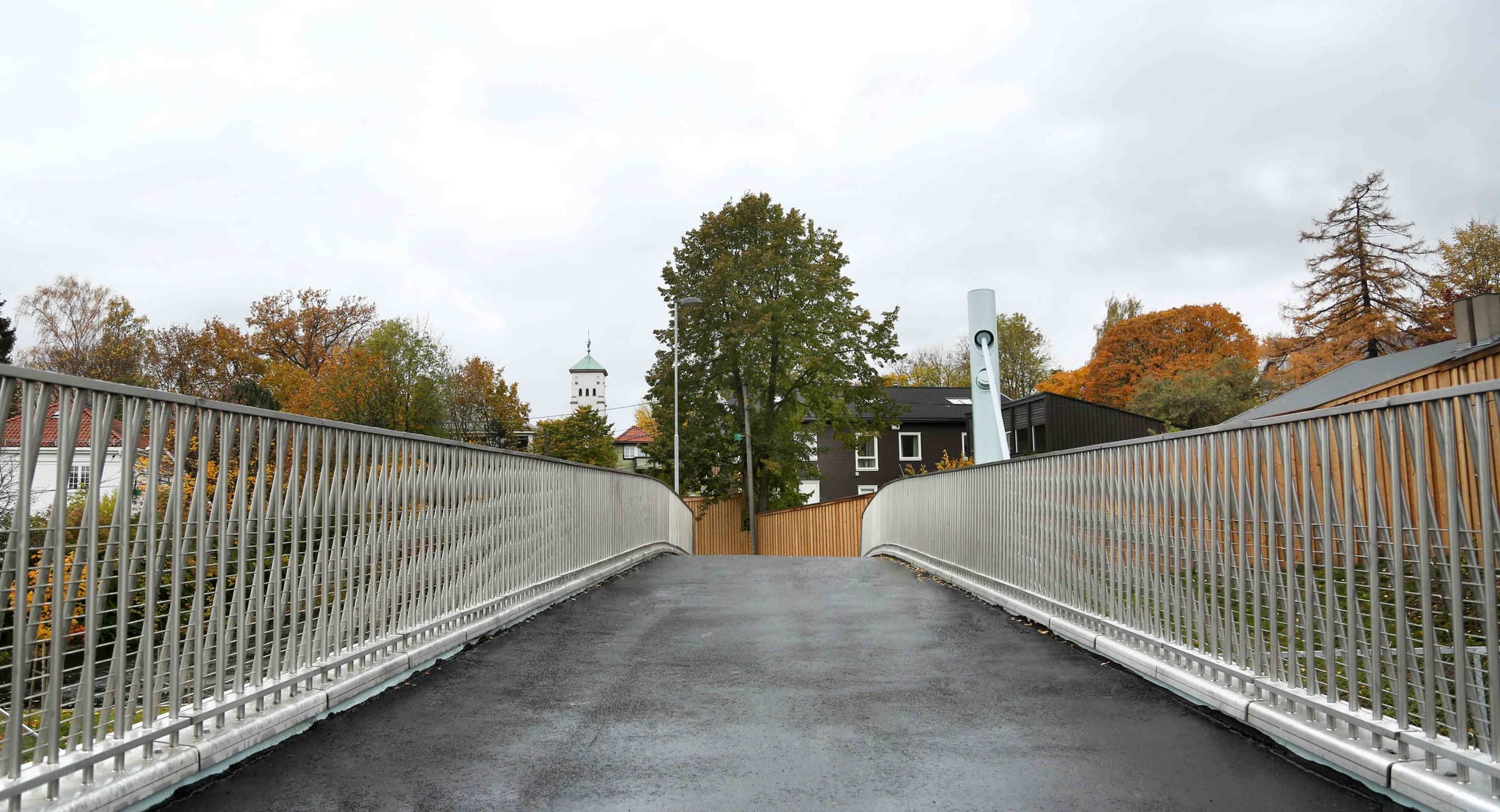 looking over a bridge, buildings and trees at the end of the bridge