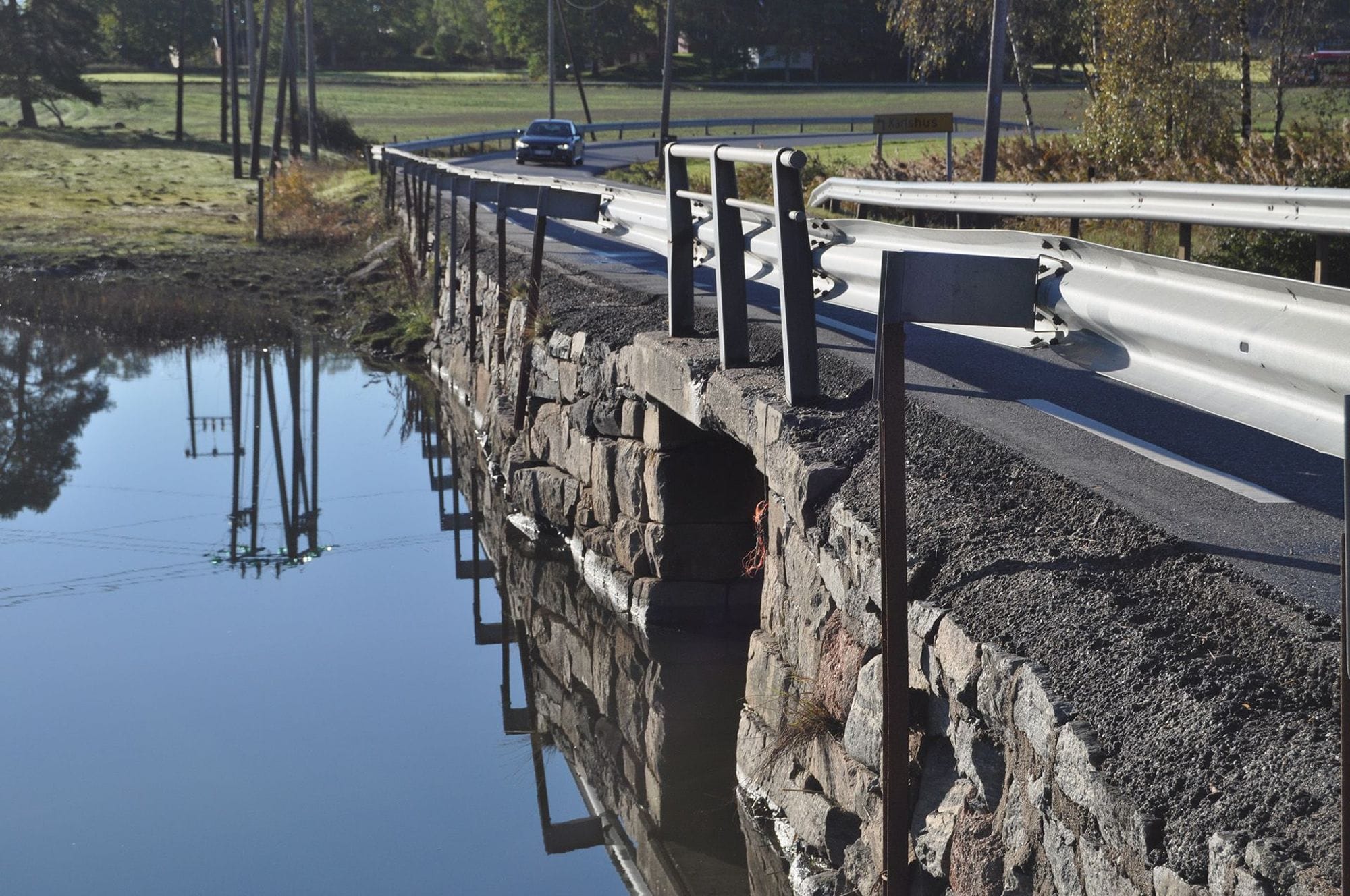 A stone-built bridge with a barrier over the water