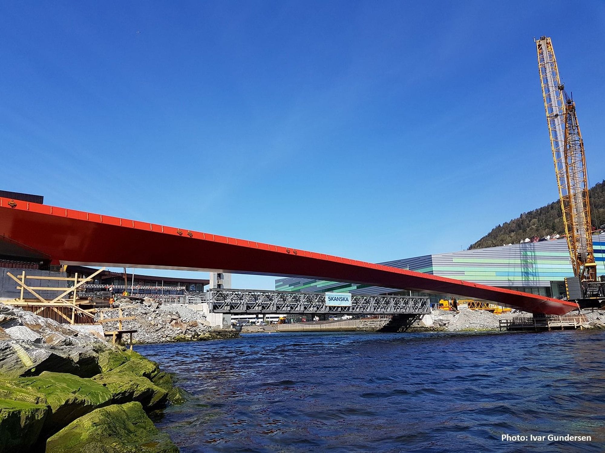 Red steel bridge over the sea and yellow crane on one side