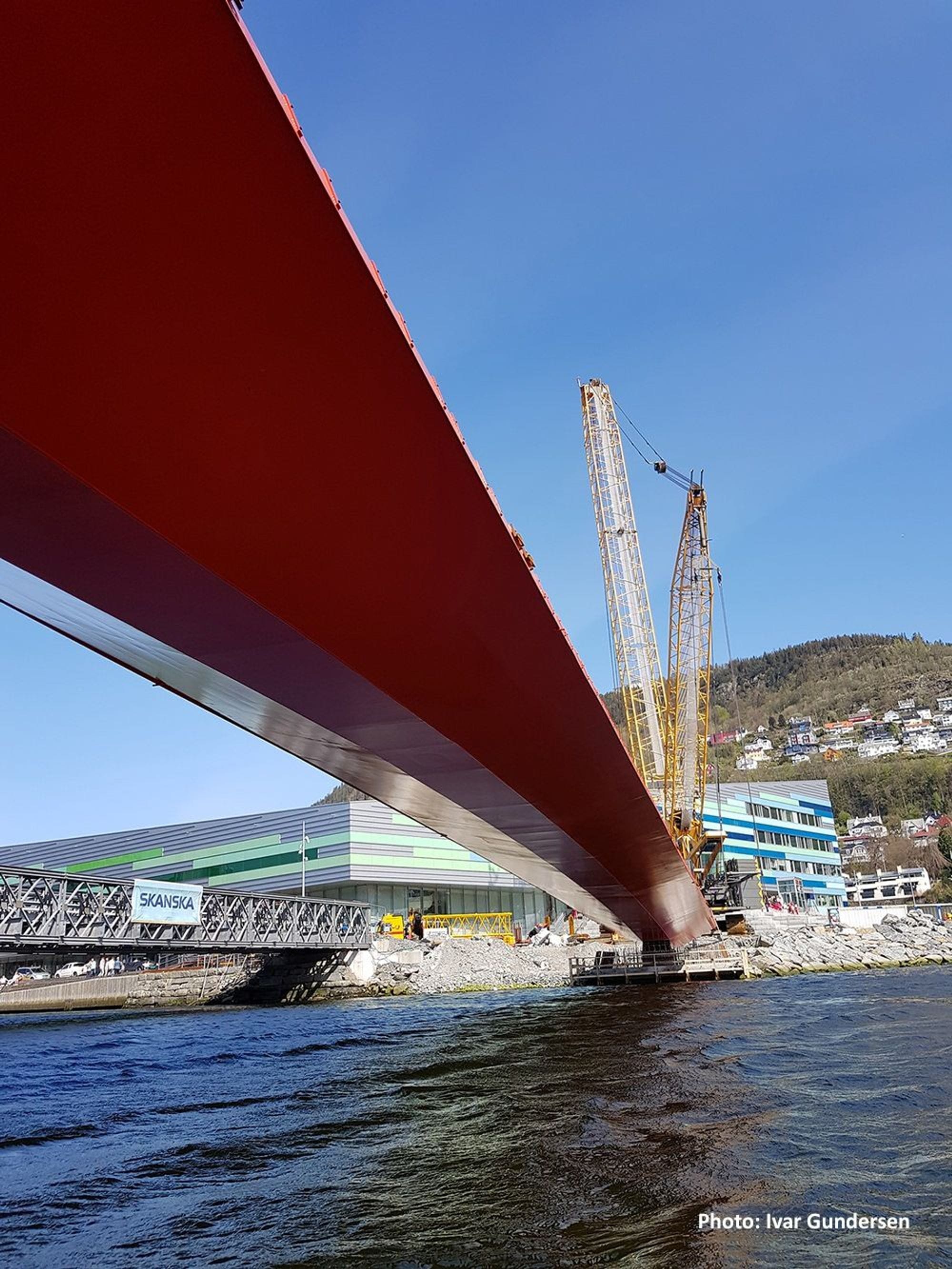 Red steel bridge from under and yellow crane in the backgroun