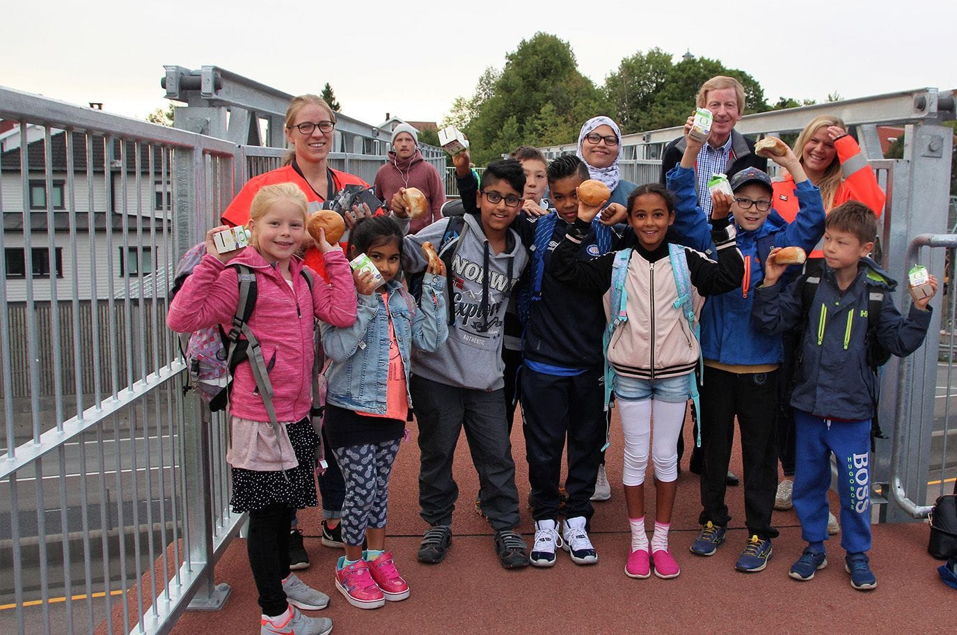 Children and 4 adults standing on the new foot bridge, posing for the camera looking happy