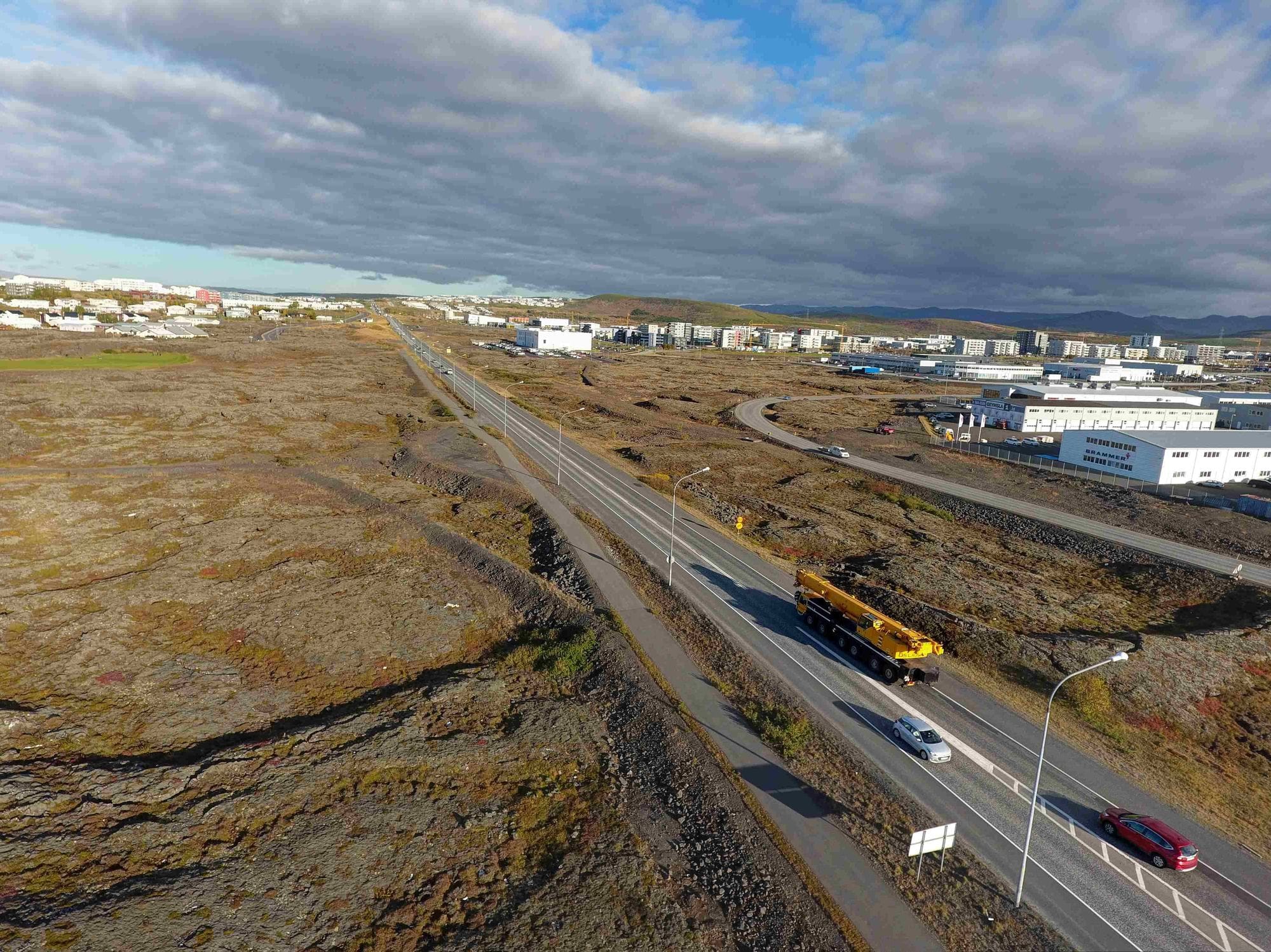 Overview of a populated area and new roads in lava fields with cars driving on the road