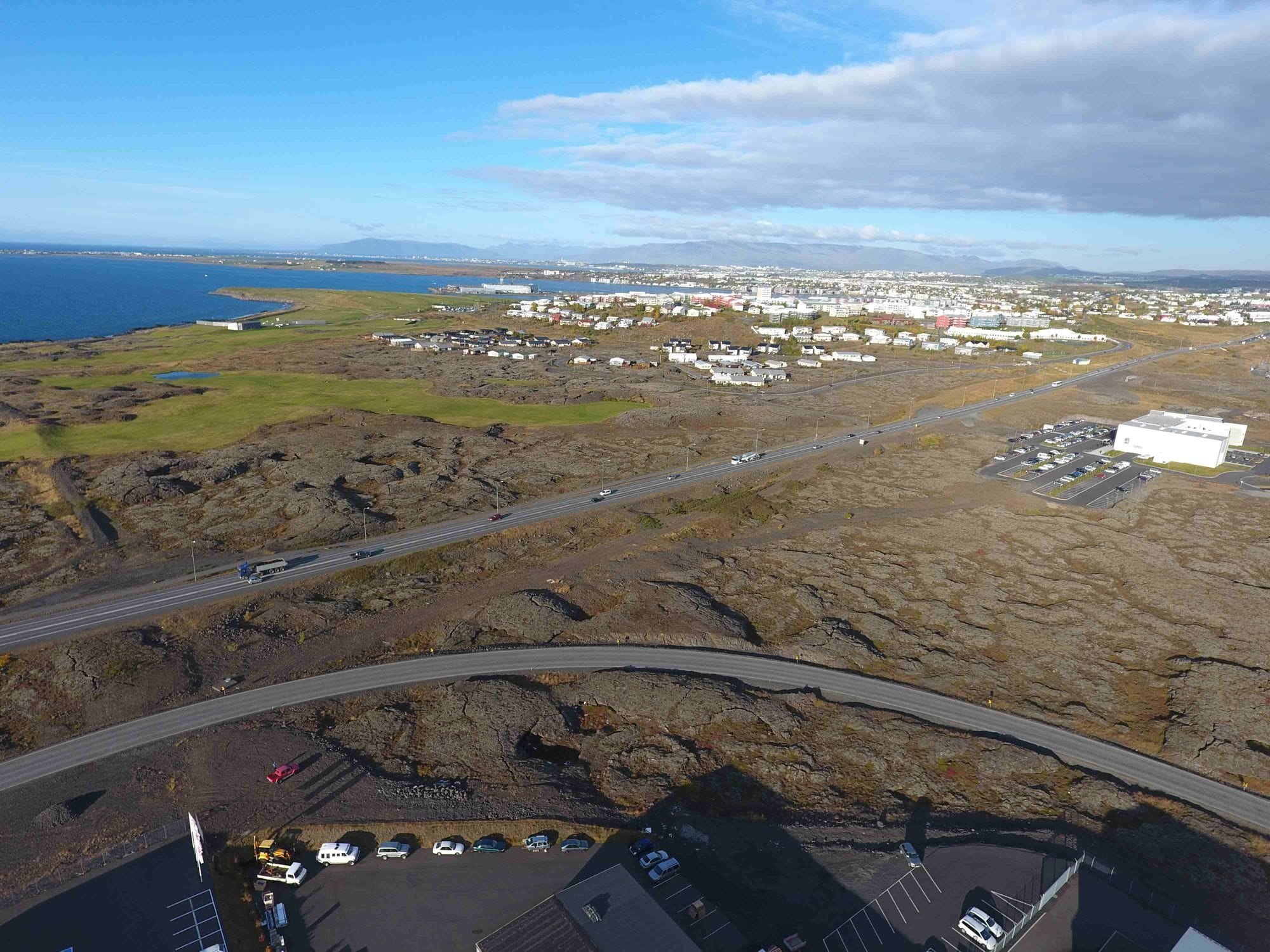 Overview of a populated area surrounded by lava fields, picture shows roads before changes: one straigth road and one curved