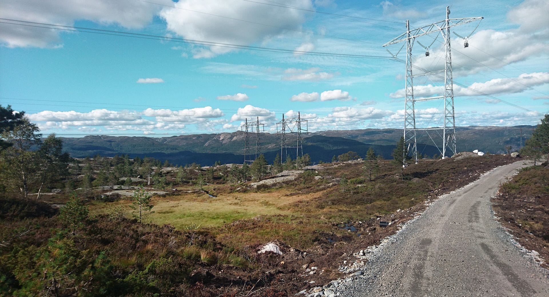 Power lines in nature with blue sky and white clouds