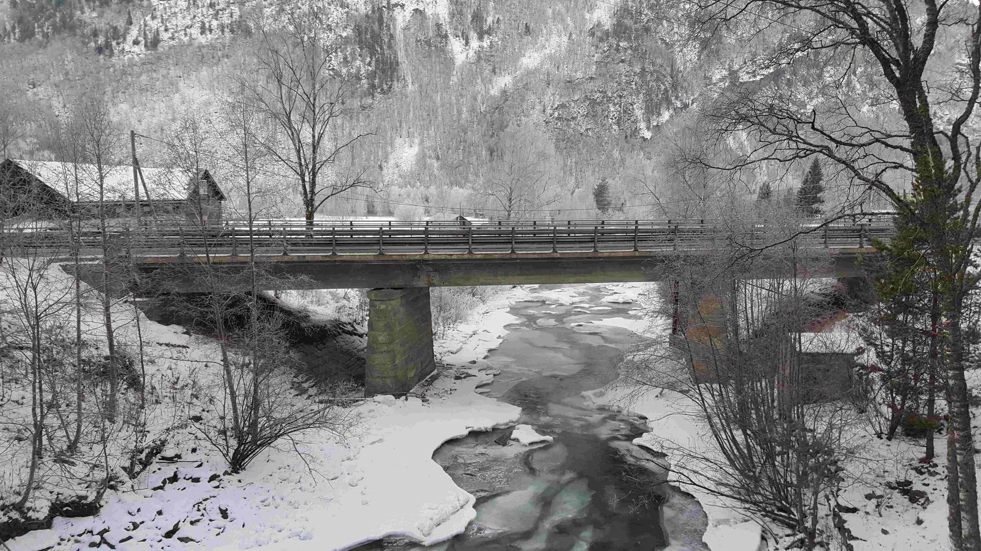 Old bridge over a river and the environment covered in white snow