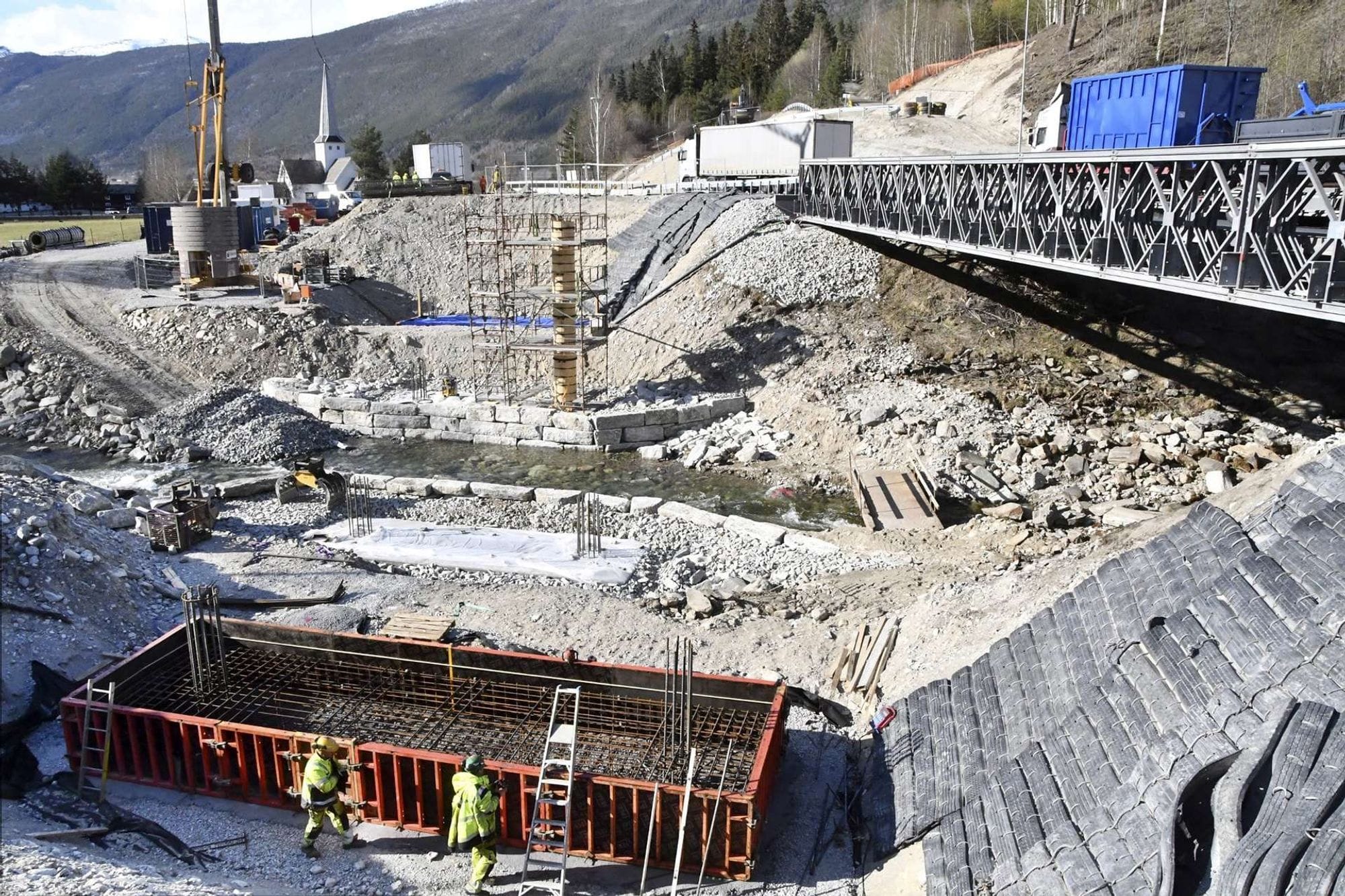 Bridge in the building phase. Working site seen from above and two men working in yellow working outfit.