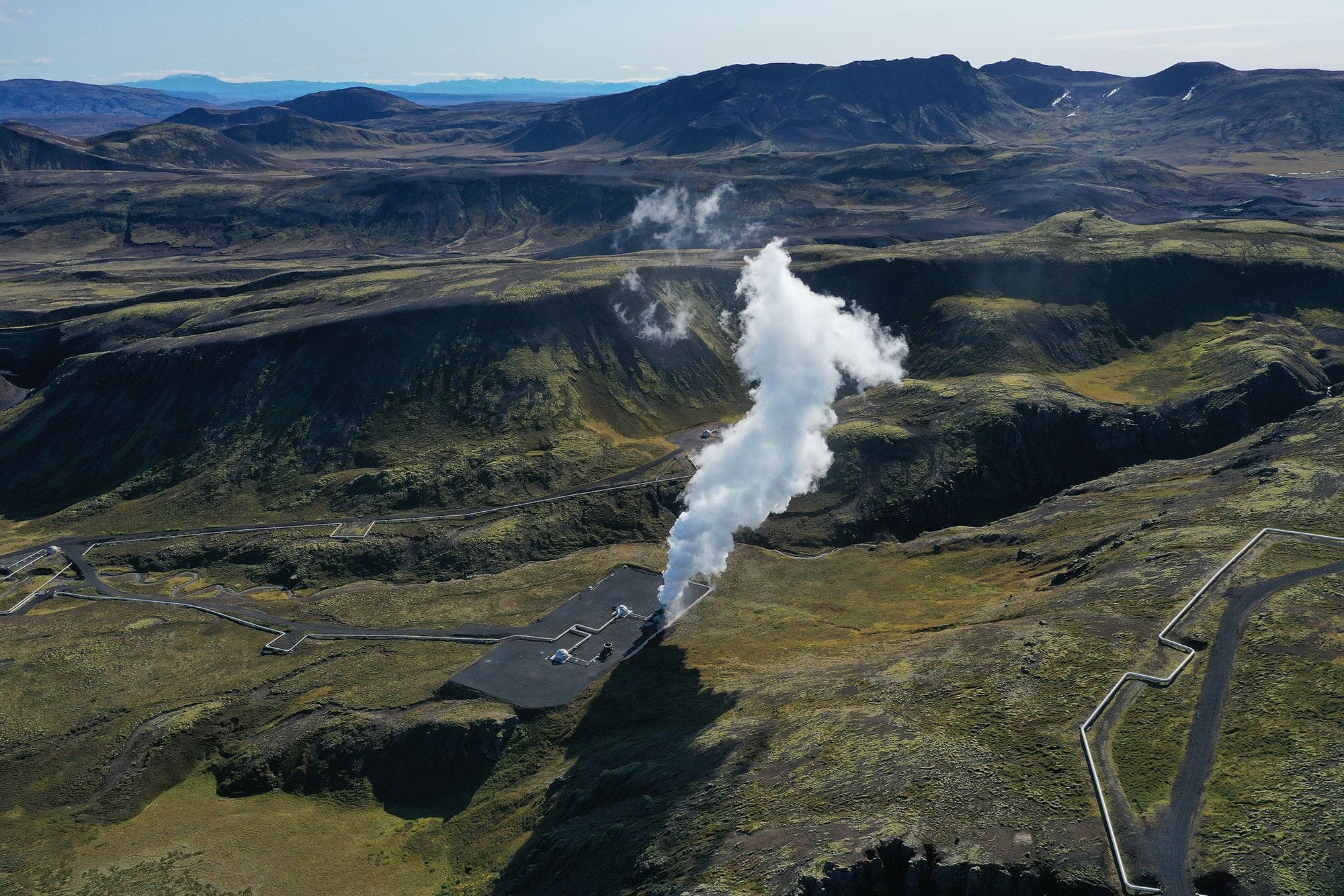 huge smoke arising from a plant in the middle of a beautiful landscape