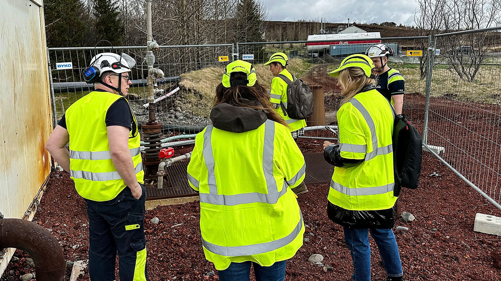 Five people with their backs turned are standing at a construction site