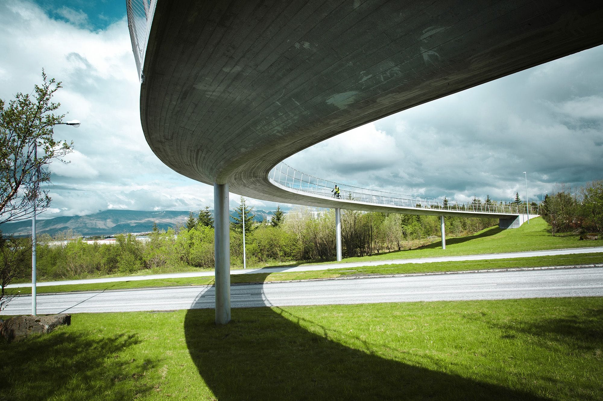 A view from underneath a pedestrian bridge, a cyclist is on the bridge