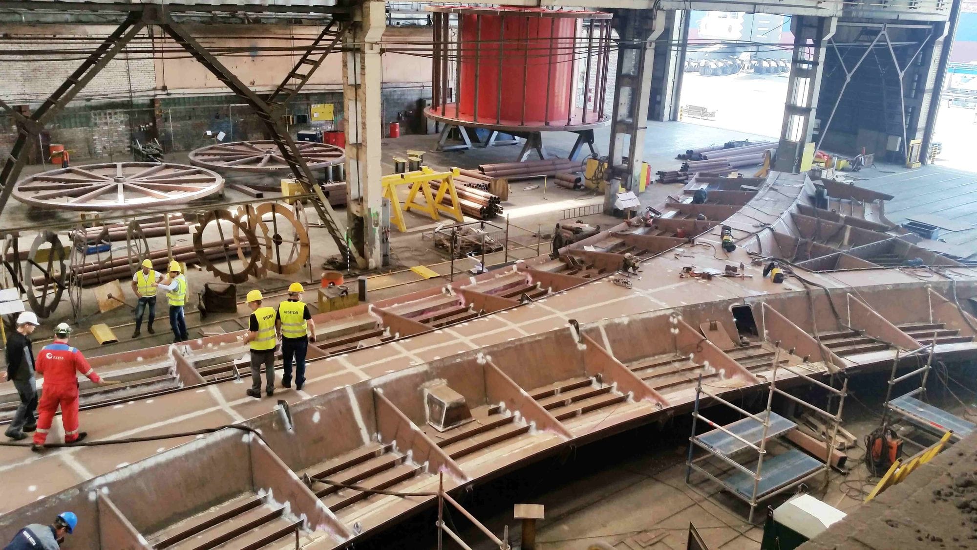 two of 16 parts of the bridge being built and laid out inside a construction workshop, men working on the building workshop