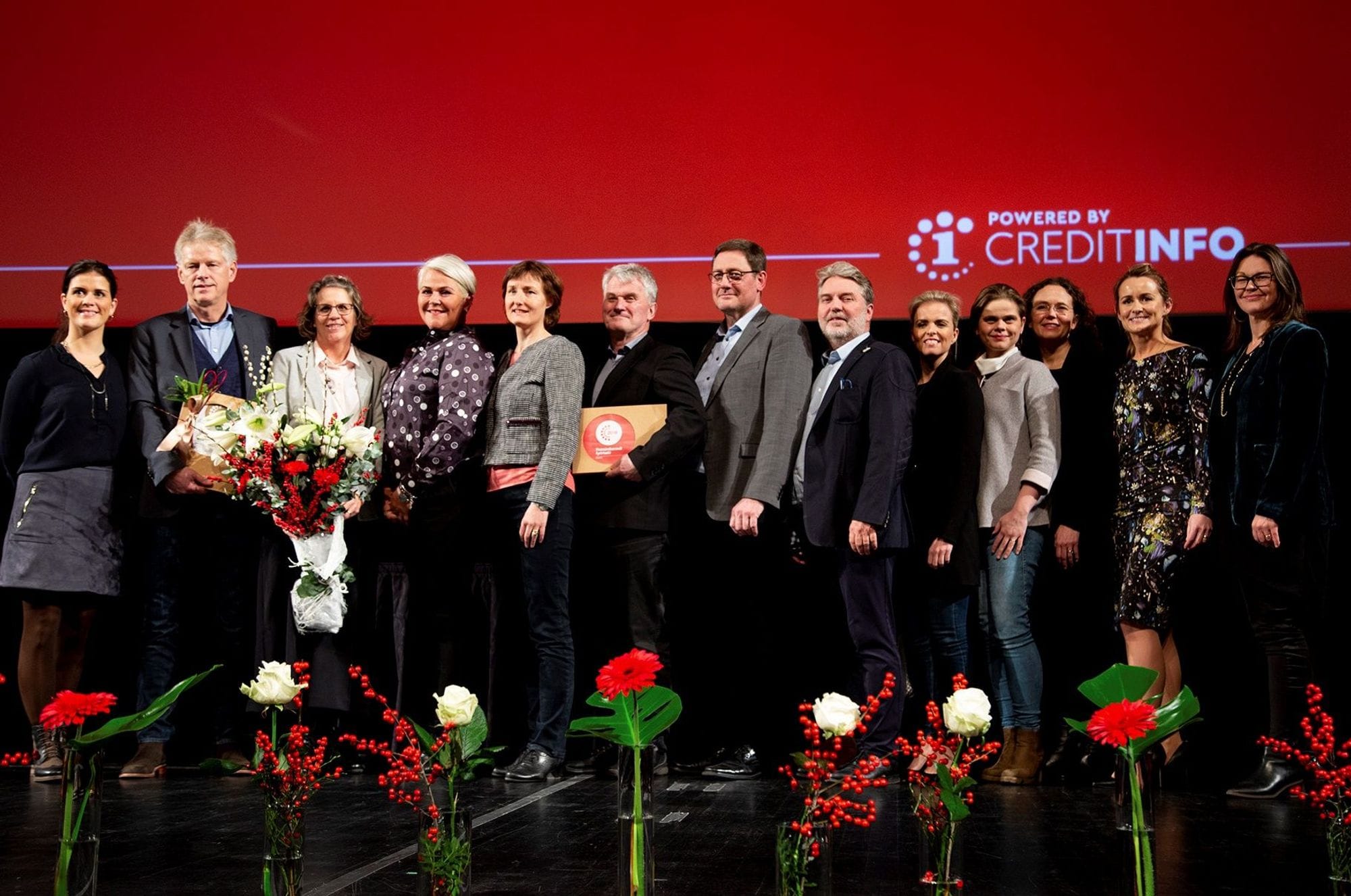 13 people from EFLA standing in row receiving a price, red and white flowers in front of the people and red background branded with Credit info
