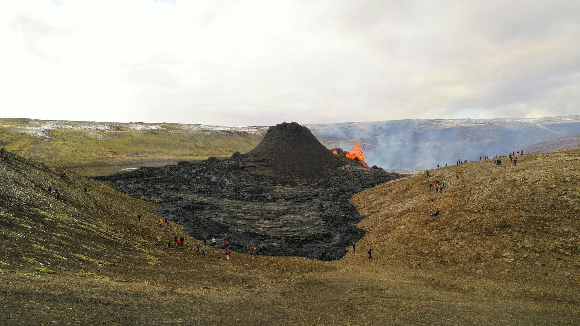 A large crowd of spectators gathers around the eruption
