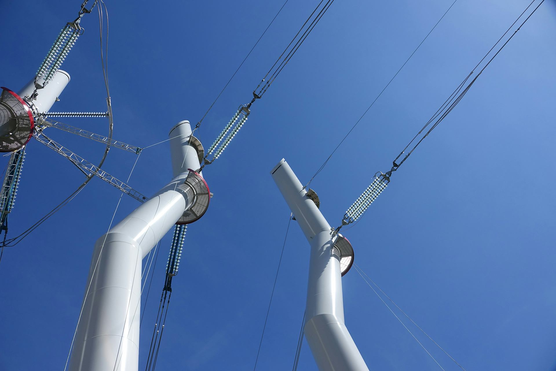 A close up view of three white metal transmission tower's peak