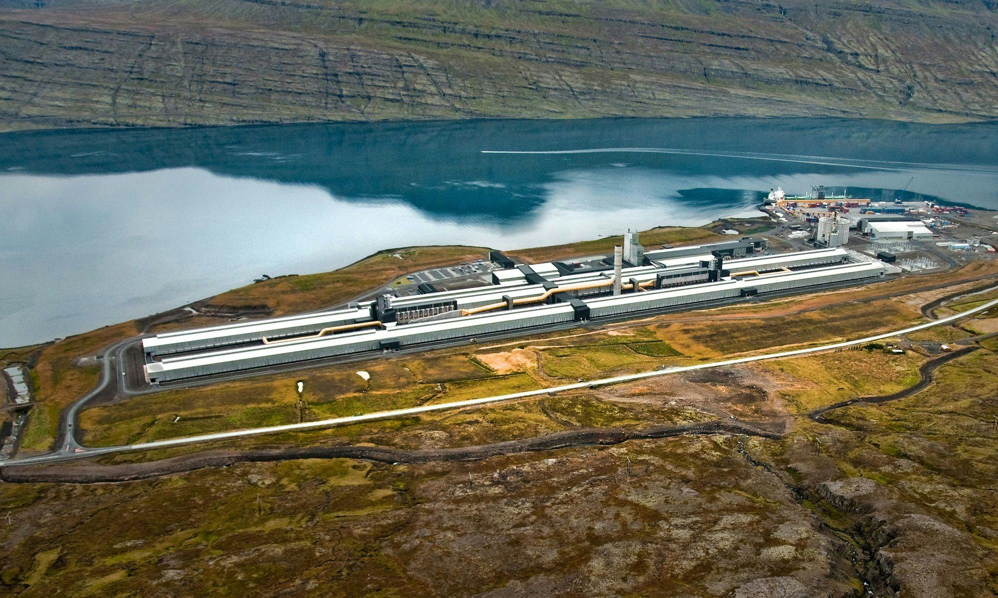 An aluminum plant in a fjord seen from above, blue sea and mountain slopes