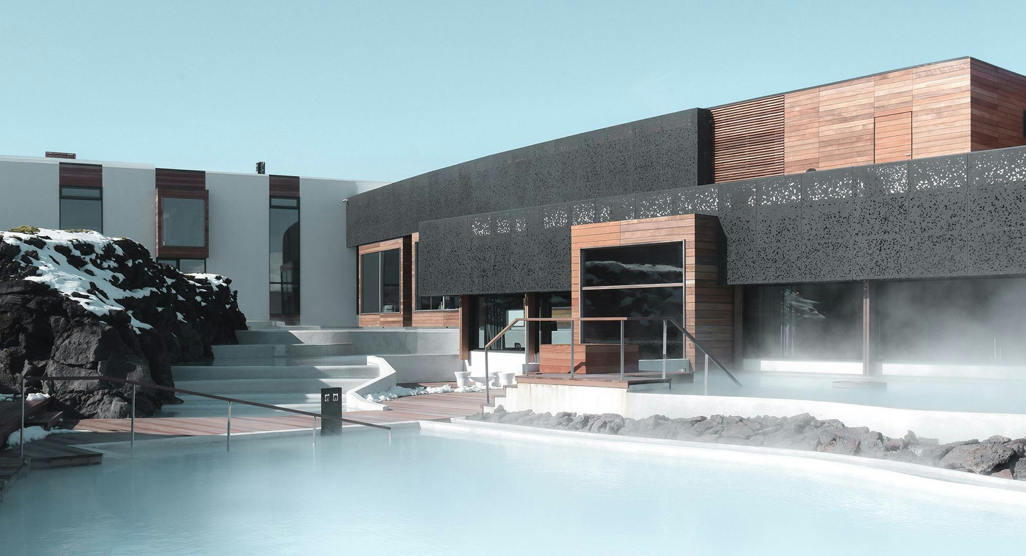 Computer rendering of a modern concrete and wooden building, blue lagoon in the foreground with snow covered lava on the left bank 