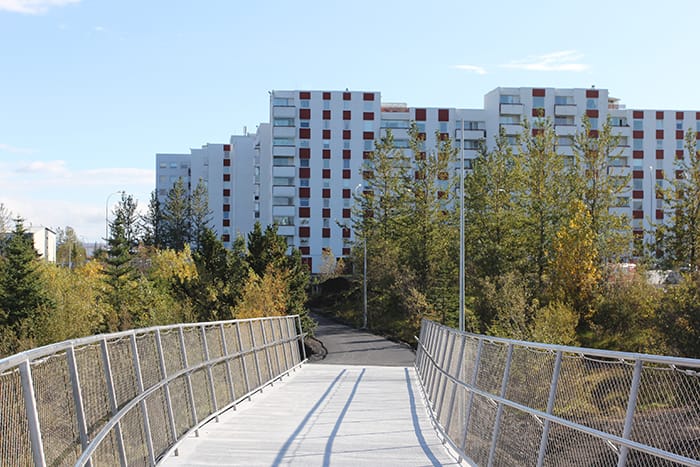 A pedestrian bridge leading towards a white block building