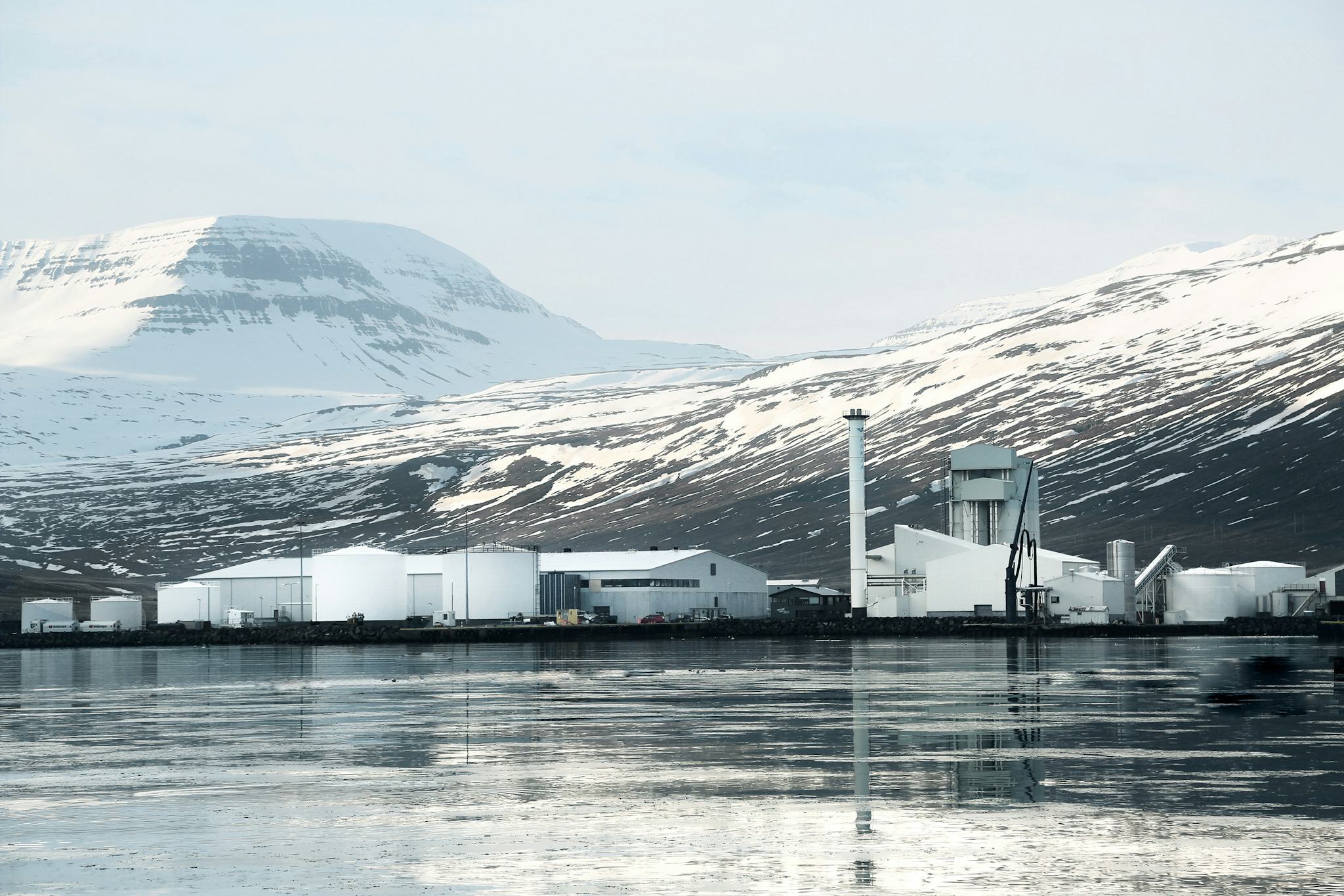 A factory on the quay, snow-capped mountains in the background