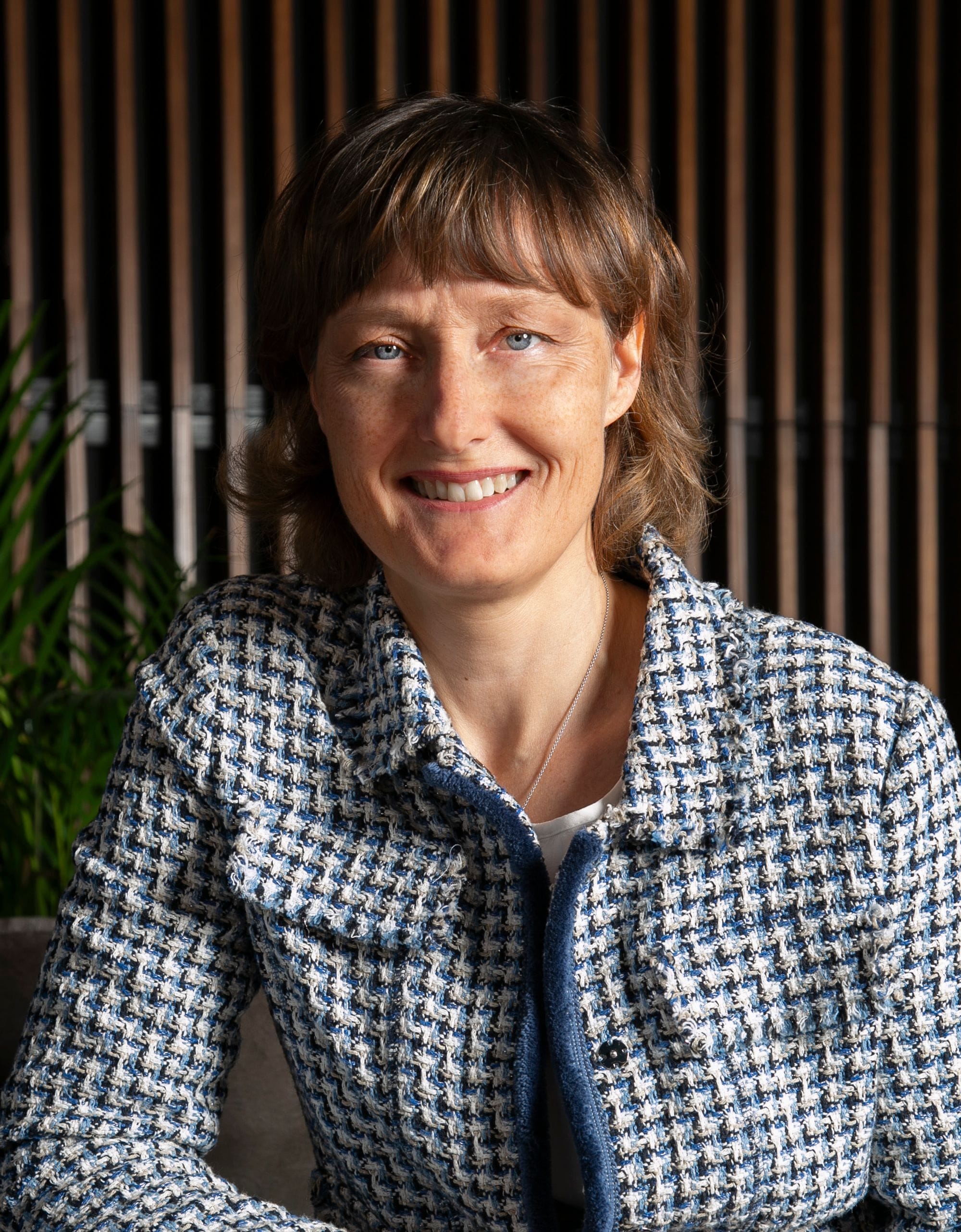 Portrait of a woman, green plants and wooden panel in background