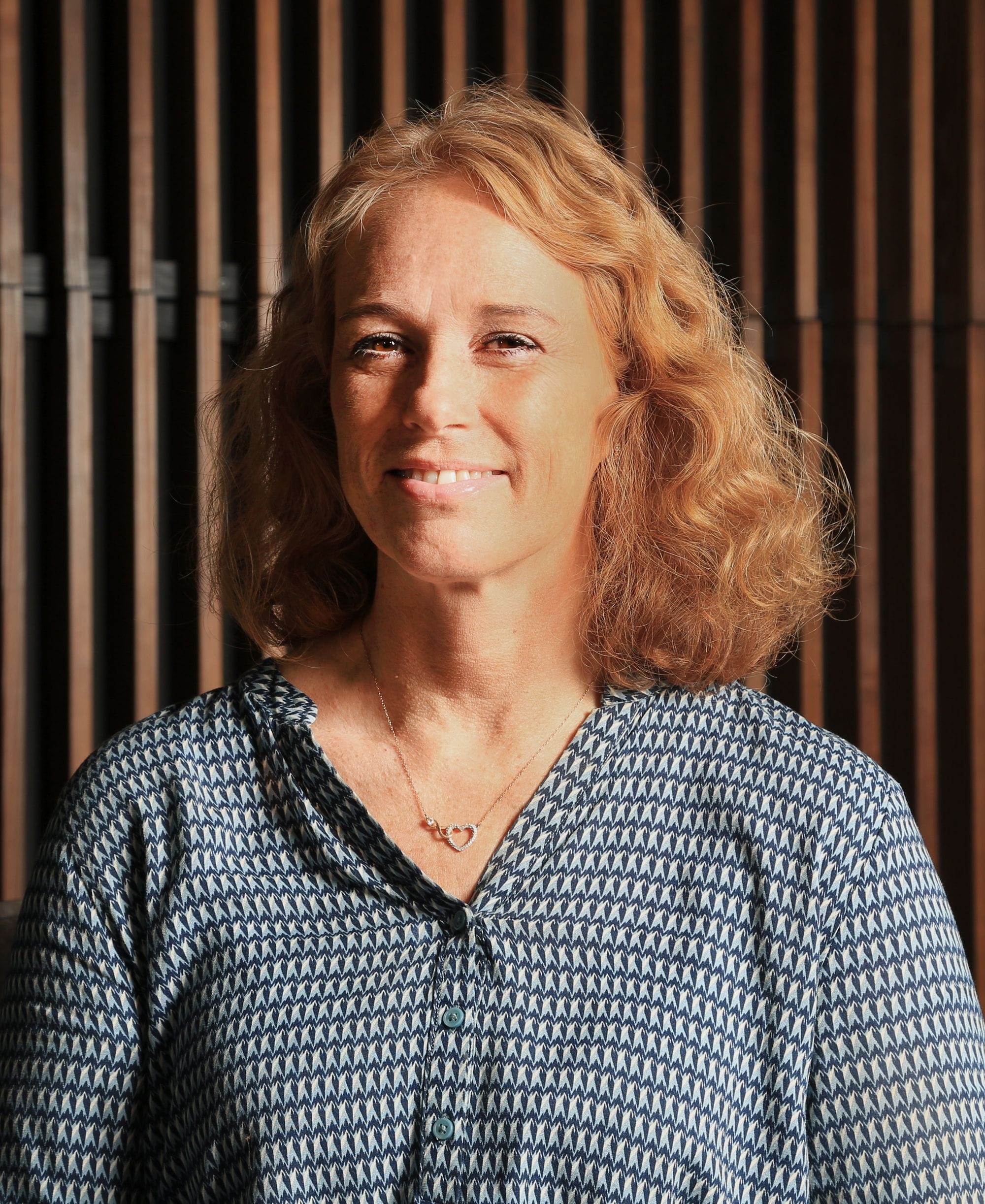 Portrait of a woman, green plants and wooden panel in background