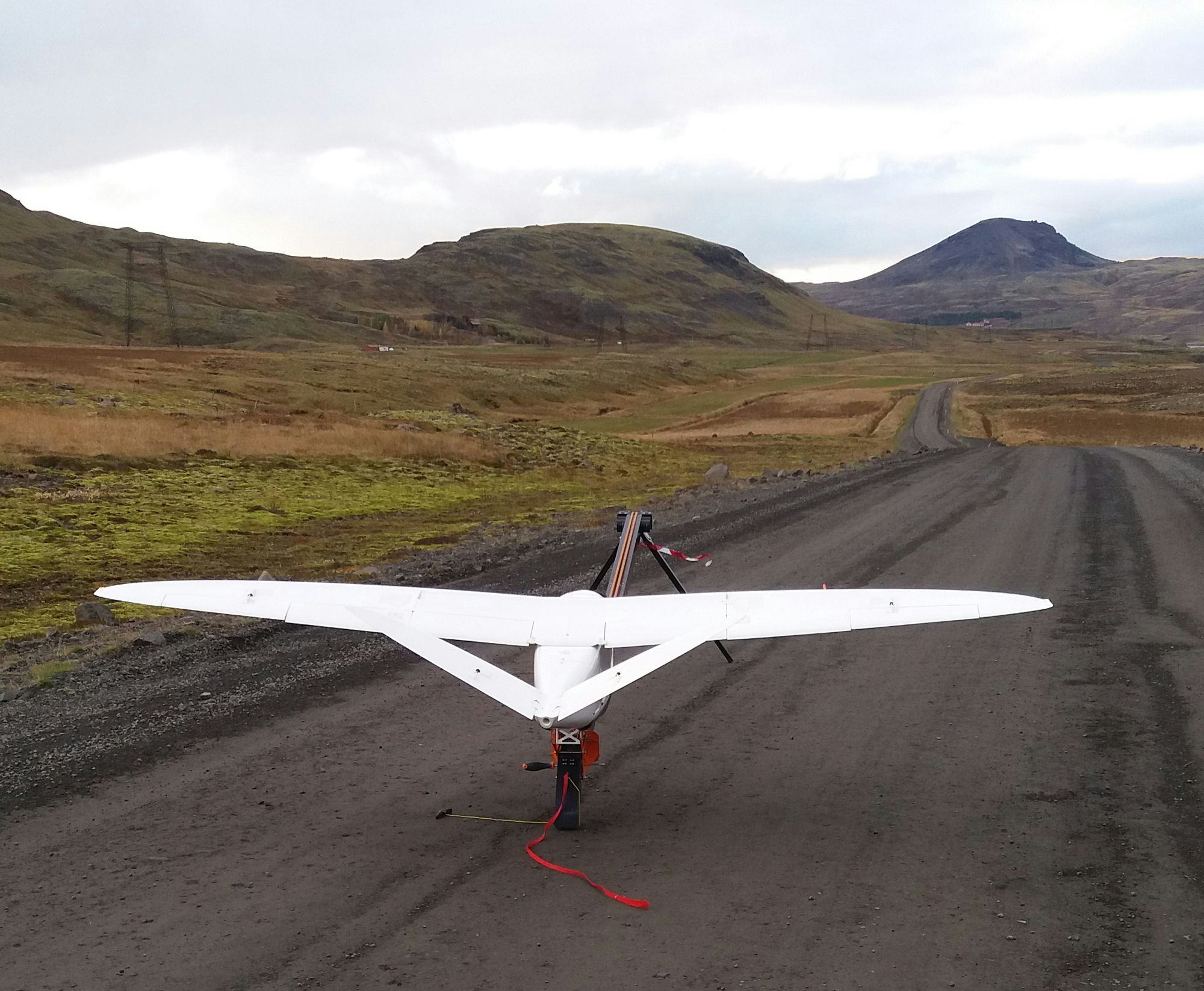 a white drone ready to ascend on a gravel road