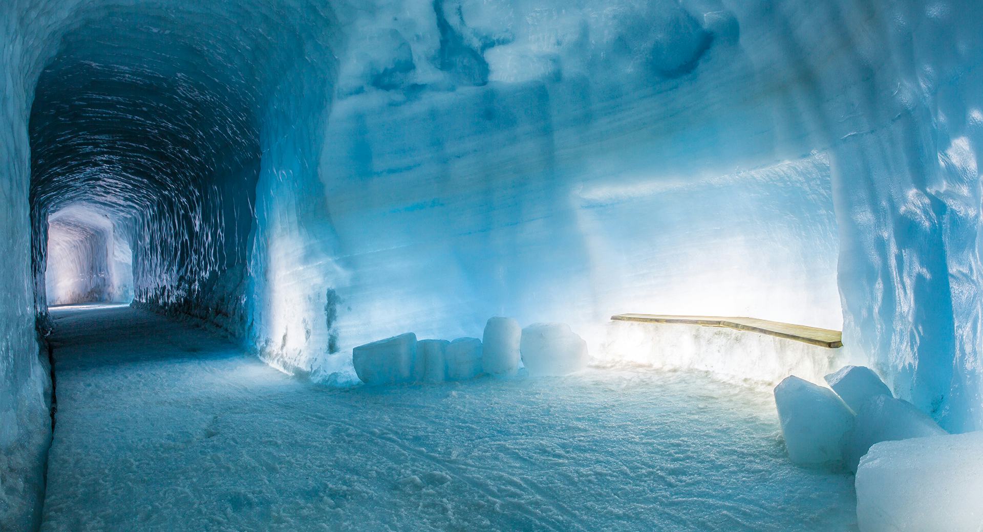 Inside of an Ice cave with a bright wooden bench attached to the wall 