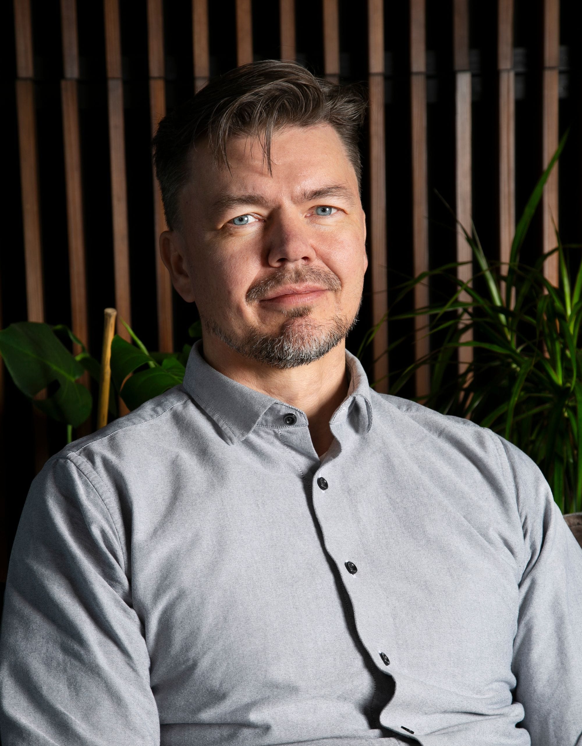 A portrait of a man, wooden panels and plants in the background