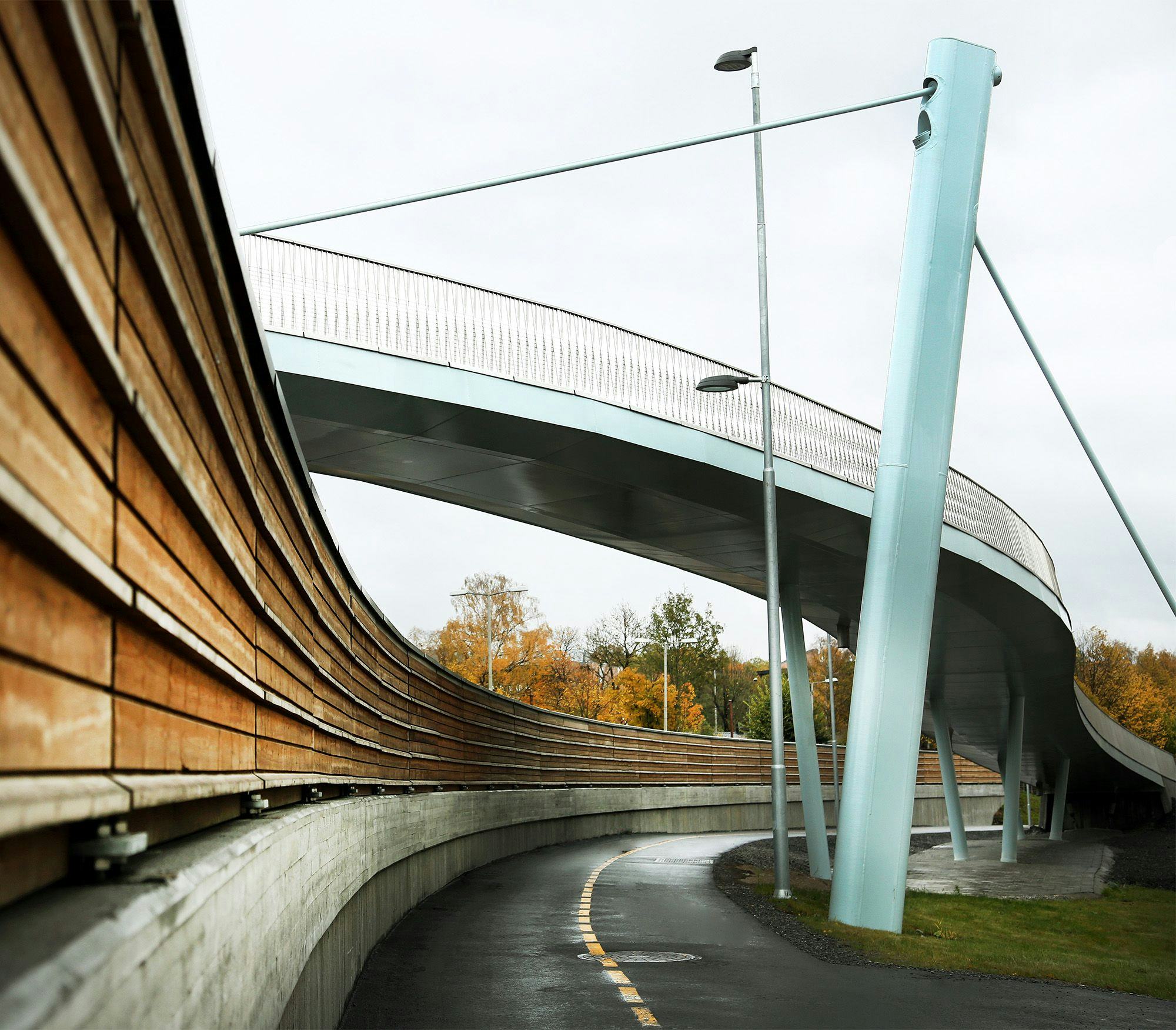 A concrete pedestrian bridge and a walking path with wooden rails